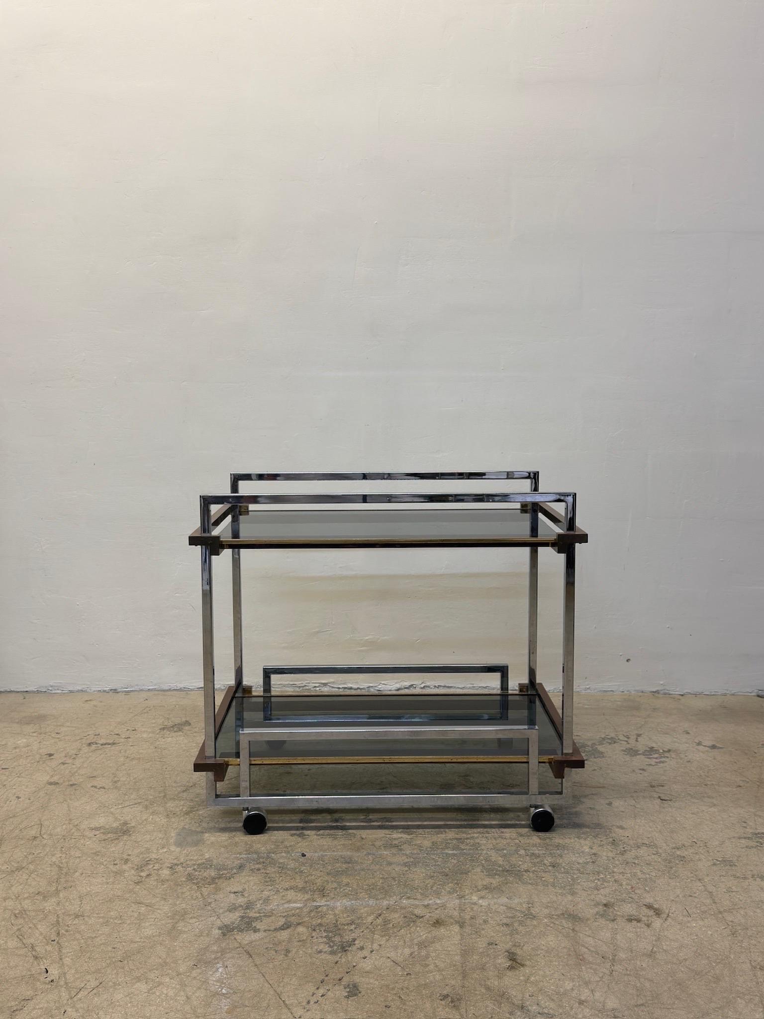 Two level smoked glass top bar cart or trolley with a mixed metal frame made from chrome, brass and copper square tubes on casters designed by Willy Rizzo circa 1970s.