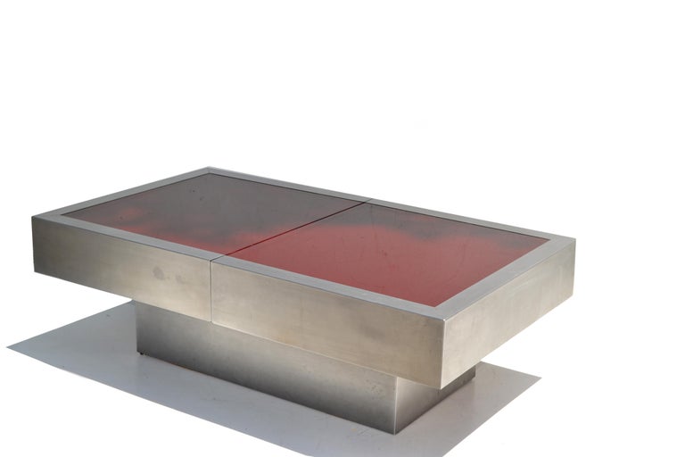 Italian Mid-Century Modern Willy Rizzo expandable cocktail table in brushed Steel with 2 red glass tops.
The table expands outward from each side from 47 inches to a maximum of 65 inches.
The interior is a polished chrome bar for bottles and drink