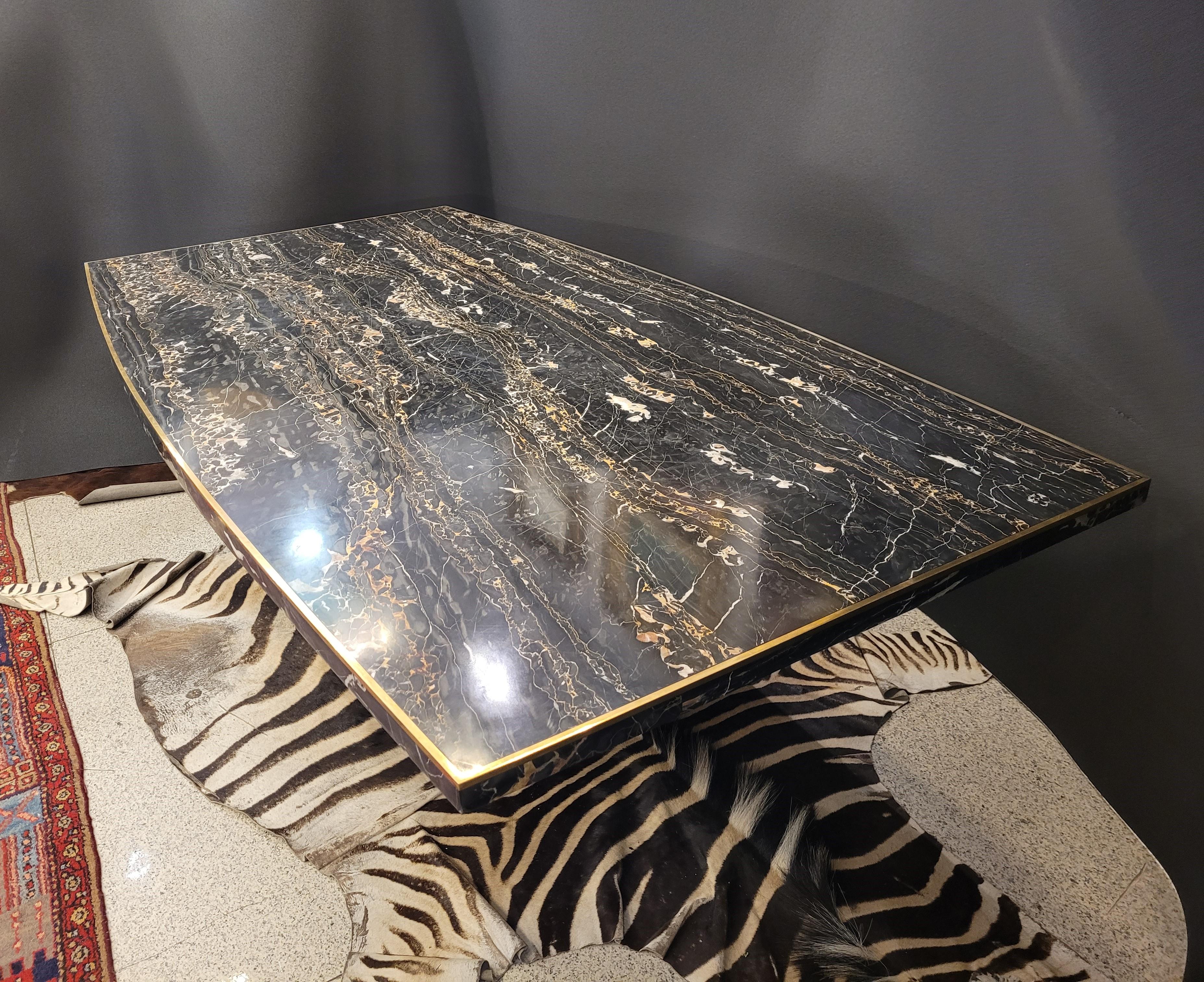 One of a kind  dining table in Portoro Gold marble, with brass profiles, signed on the base by Willy Rizzo, designed in the 1970s. The top has a rectangular shape, rounded on the longest sides. The foot is solid, and is made up of vertical marble