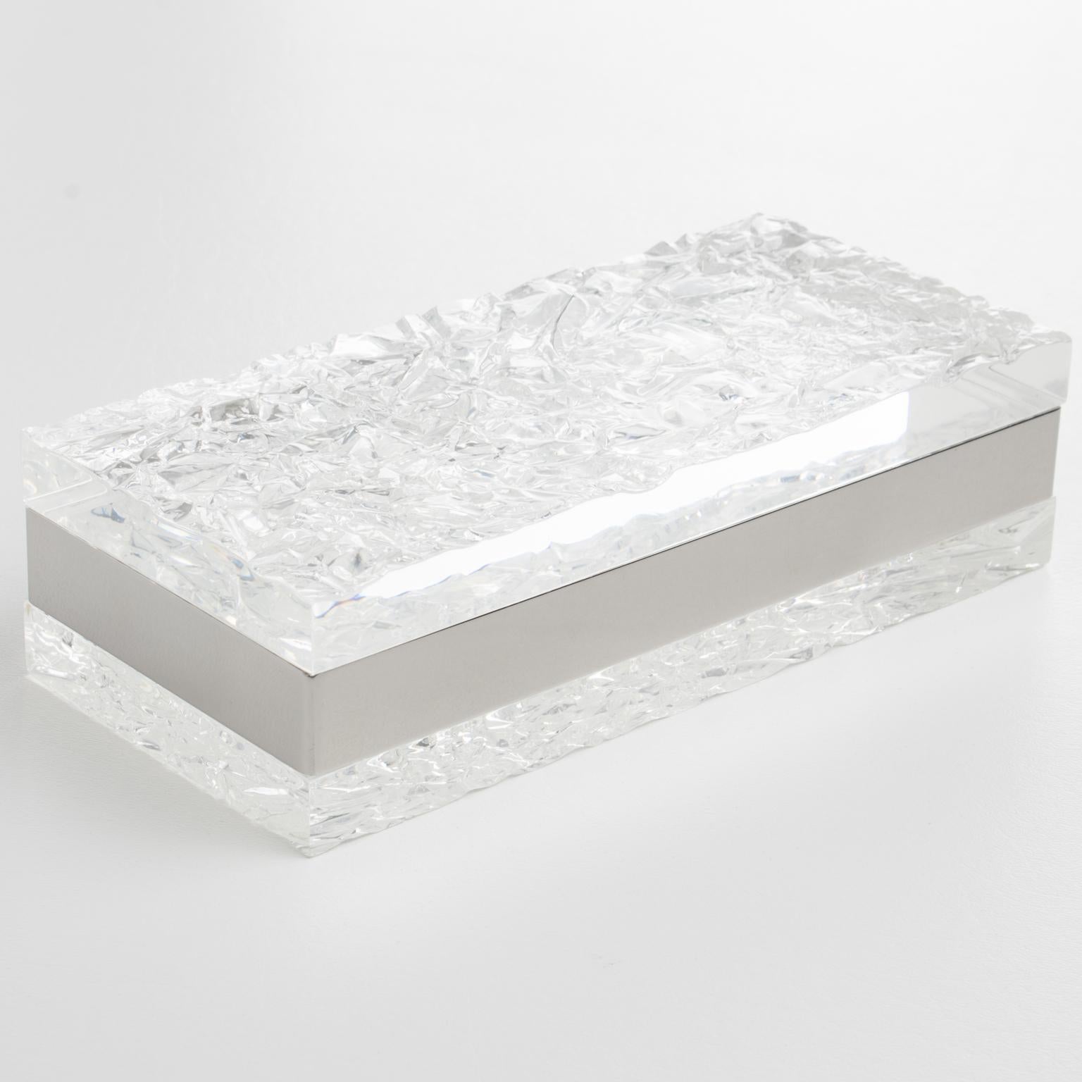This refined modernist Lucite and chrome box has its design commonly attributed to Willy Rizzo, Italy. Crafted in the 1970s, the lovely decorative piece boasts a rectangular shape with an extra-thick transparent Lucite slab for the base and the lid