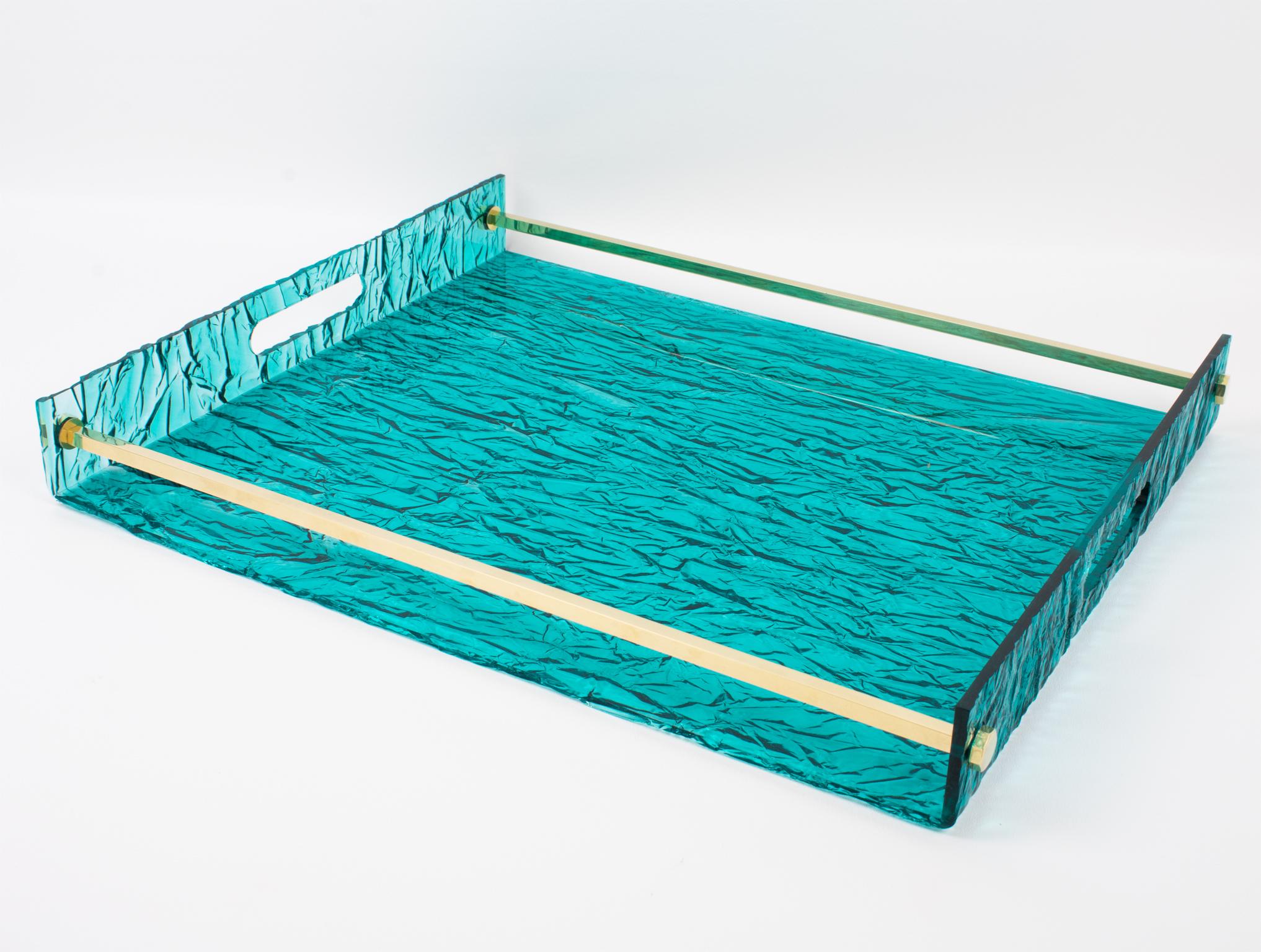 This gorgeous 1970s modernist barware serving tray has its design attributed to Willy Rizzo. The geometric shape boasts a gilded brass metal gallery and turquoise blue-lagoon textured pattern Lucite. The crystal transparent Lucite has a stunning