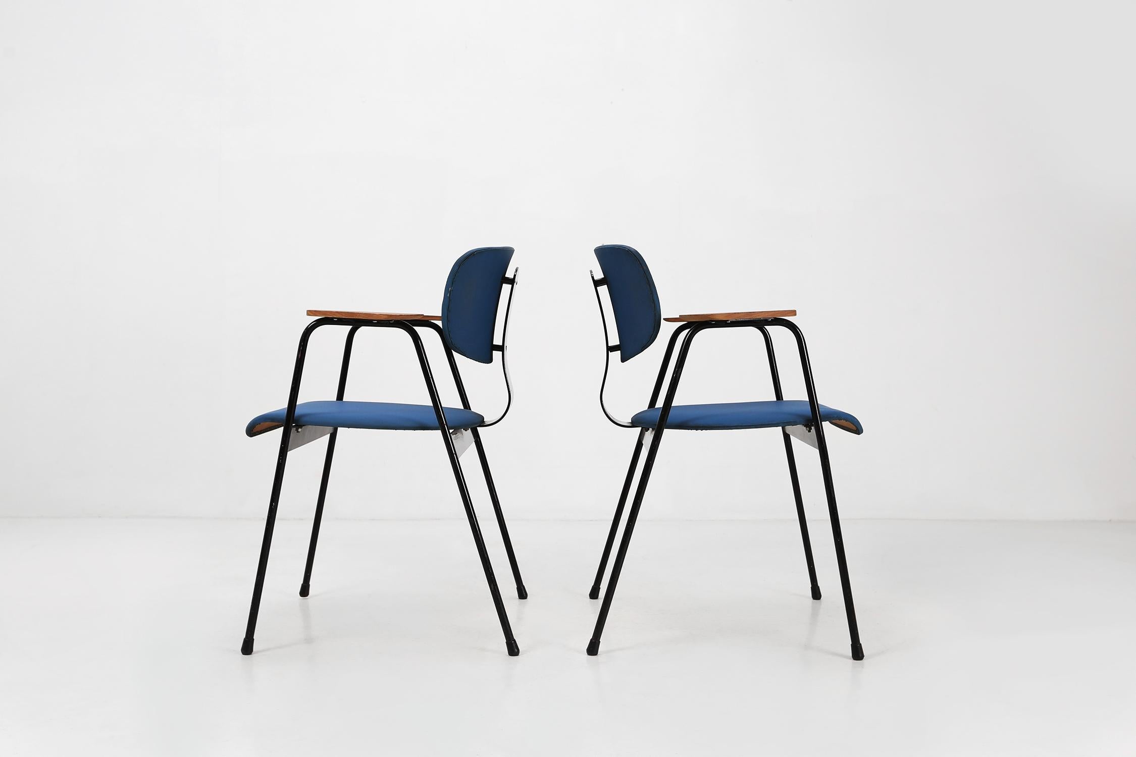 Two chairs by designer Willy Van Der Meeren for Tubax Ca.1950.
Have a black lacquered metal frame with blue vinyl seat.
The armrests are made of wood.

Van Der Meeren is considered one of the most important Belgian furniture designers of the