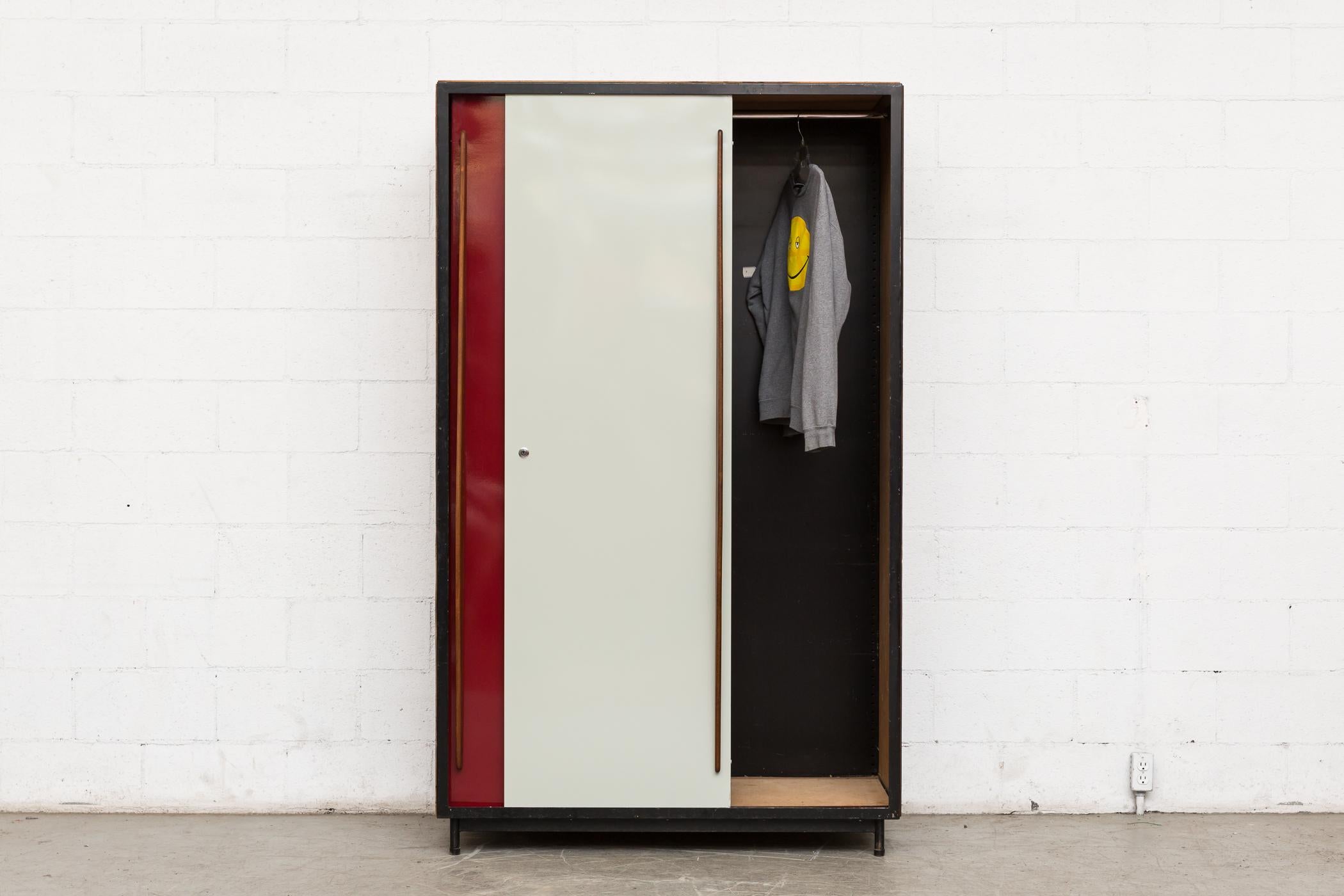 Willy Van Der Meeren large wardrobe for Tubax with wood panelled sides, tapered mahogany door pulls and red and white enameled metal doors with black enameled metal frame, Belgium, 1952. Visible wear, consistent with its age and usage.
 