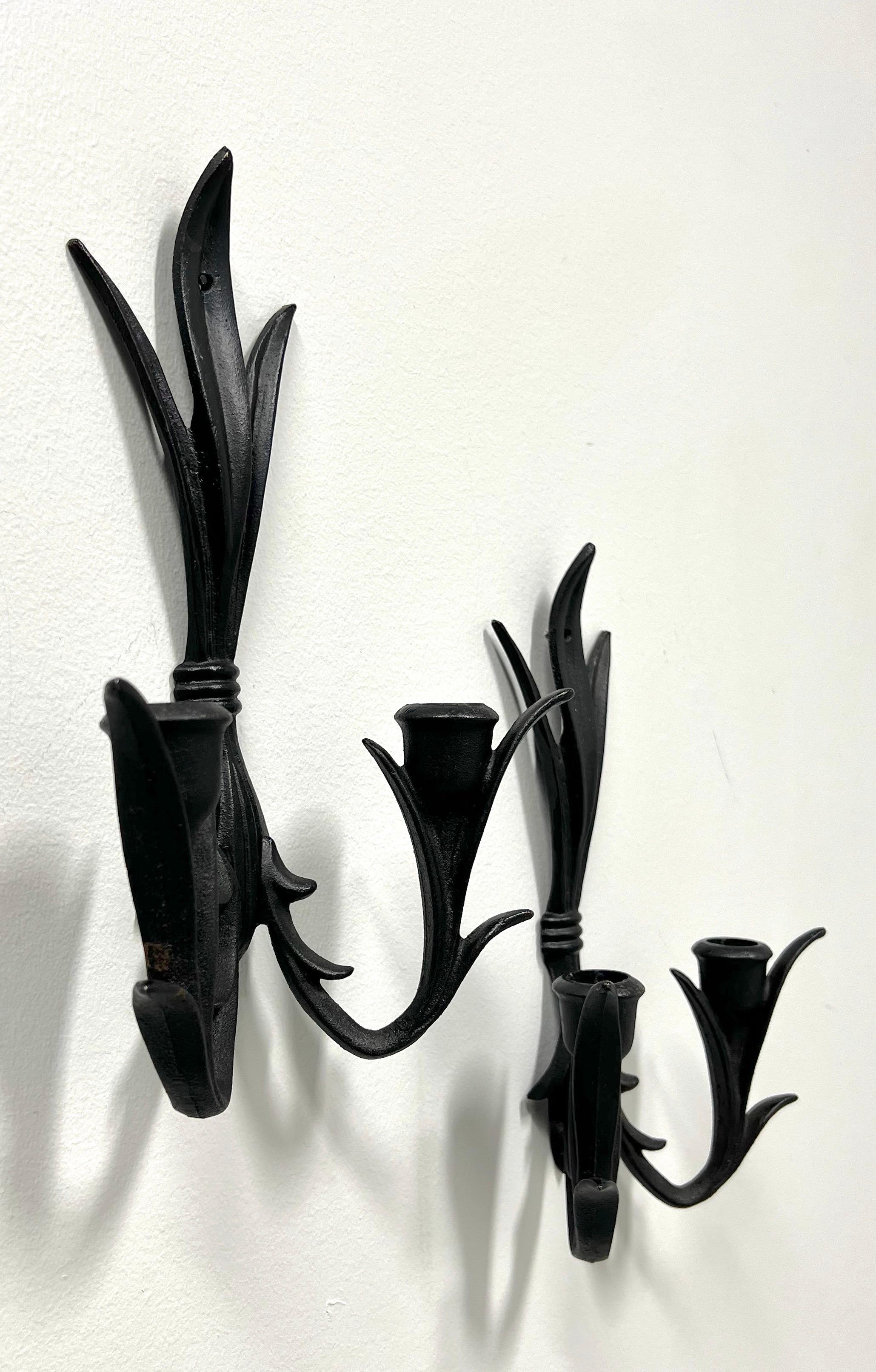 A pair of Gothic style candle wall sconces by Wilton. Solid cast iron, black in color, in a gathered sheaf of leaves design, with two arms and candleholders. Made in the USA, in the mid-20th Century.

Measures:  7w 3d 12h, Weighs Approximately: 2