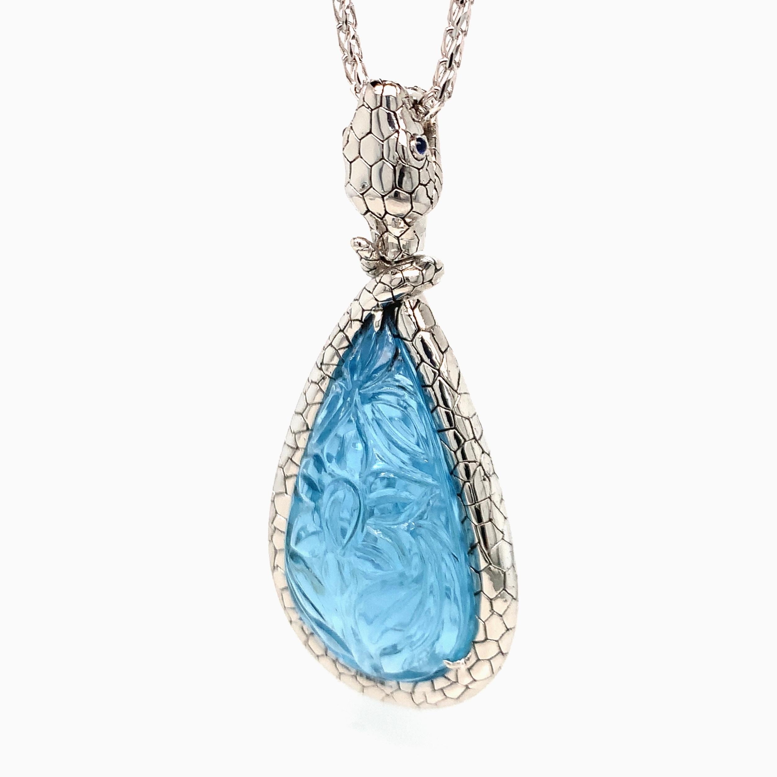 Un pendente in platino, disegnato a forma di serpente, con un'acquamarina intagliata di 55 carati. Il serpente è inciso con un motivo che dà un effetto naturale e lo rende più vivace. Inoltre, due zaffiri blu scuro tagliati a cabochon fungono da
