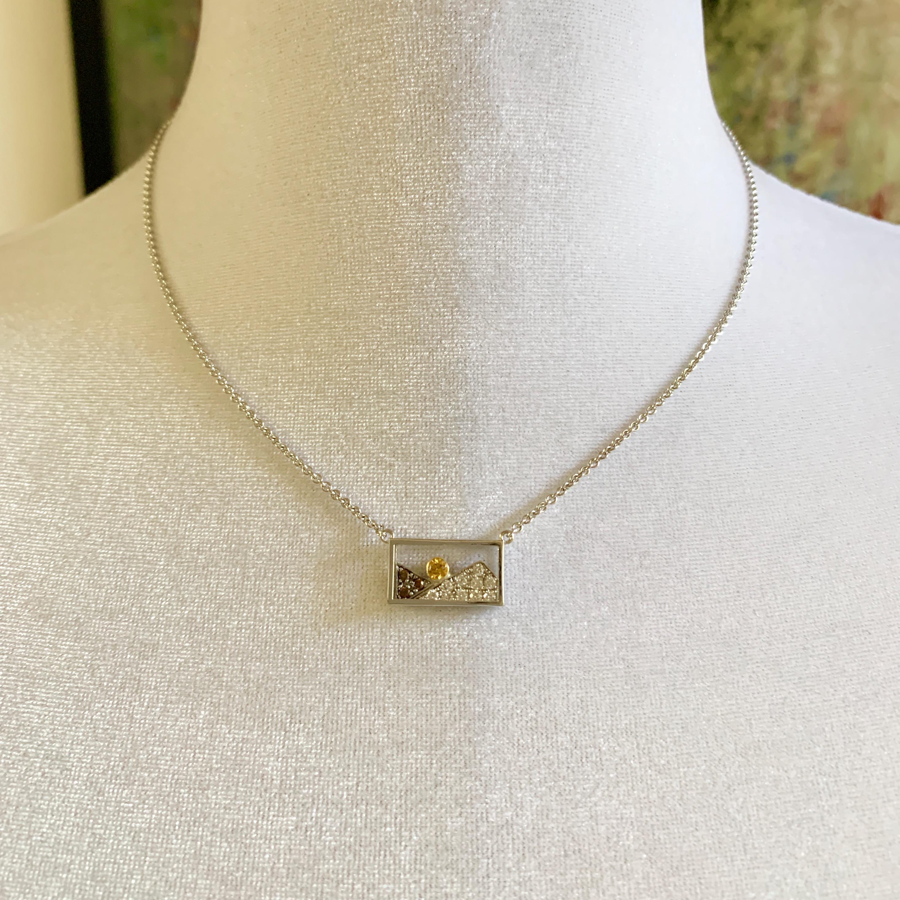 This tiny window looks out on a fiery orange sun rising between two mountains in a one-of-a-kind pendant designed by Eytan Brandes.  

The 0.11 carat 