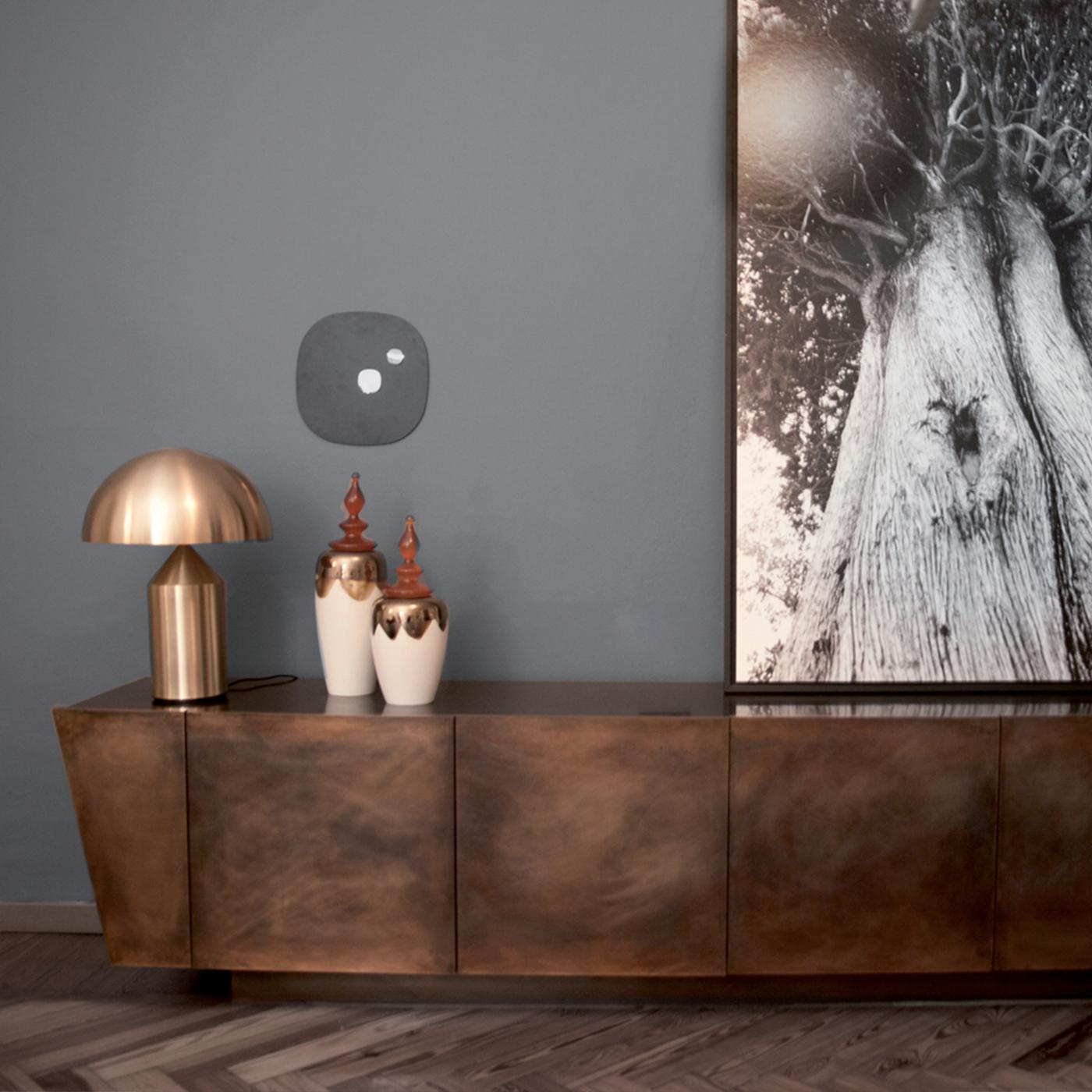 A distinctive rigor of lines, combined with a simple silhouette and warm colors give this piece a powerful allure. This sideboard is a monolith resting on a plinth base, whose structure is in Medium-Density Fiberboard covered in bronze slabs that