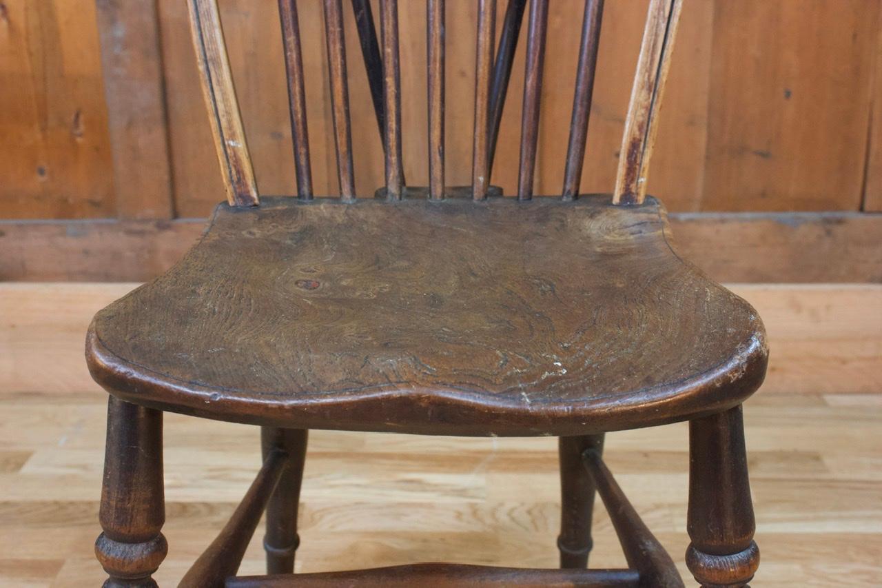 Dieser rustikale englische Holzstuhl zeichnet sich durch eine geschnitzte Holzsitzfläche aus, an der das Untergestell und die Rückenlehne direkt befestigt sind. Die Rückenlehne ist aus Massivholz gefertigt.