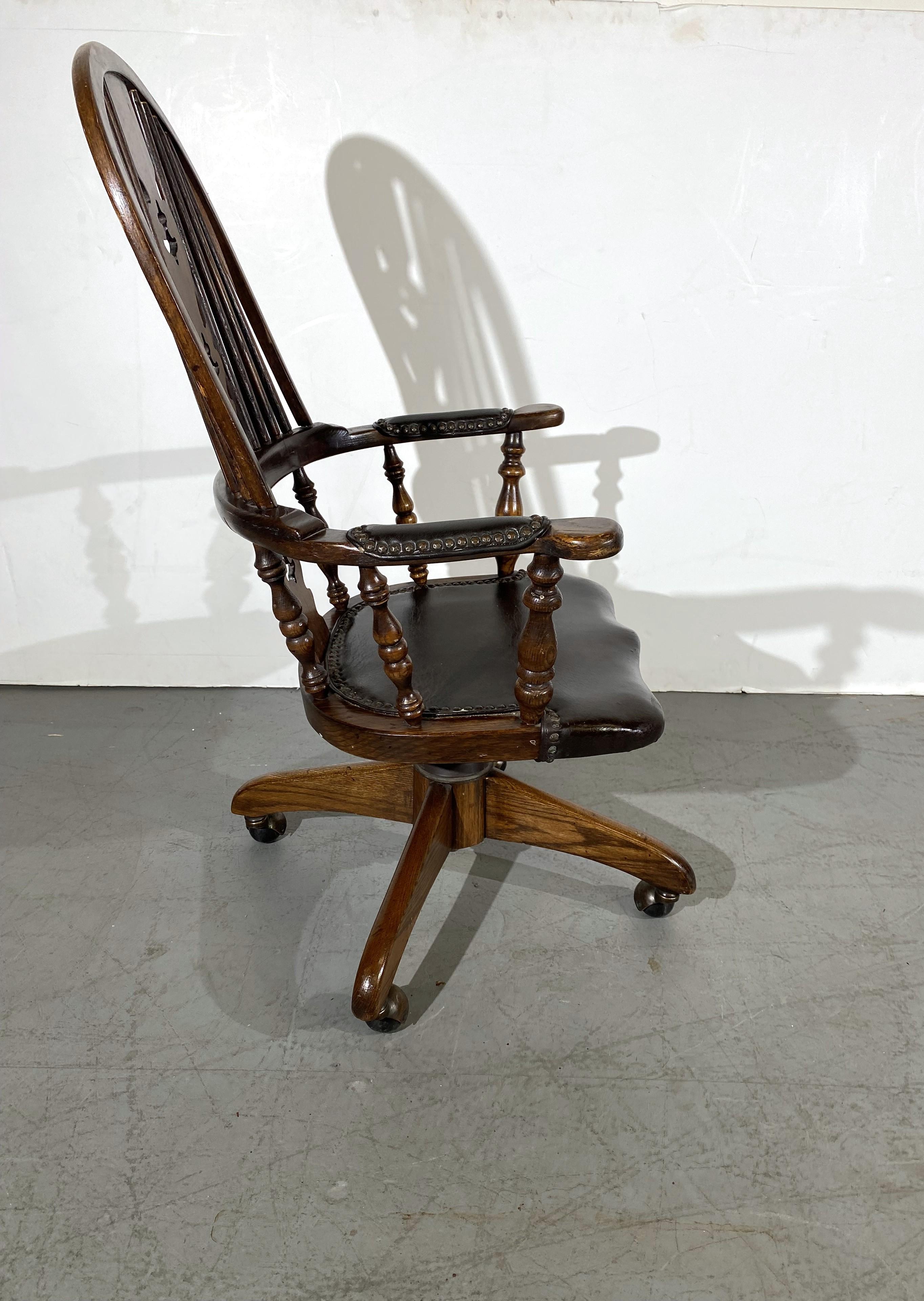 An English Windsor-style leather seat and arms swivel desk chair. 
