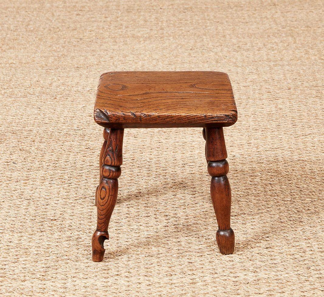 Petit tabouret fabriqué par un fabricant de chaises de Windsor du XVIIIe siècle, avec un épais plateau en orme magnifiquement patiné sur des pieds en frêne tournés et évasés.  Utilisé à l'origine pour se percher lors de la traite des vaches, sa