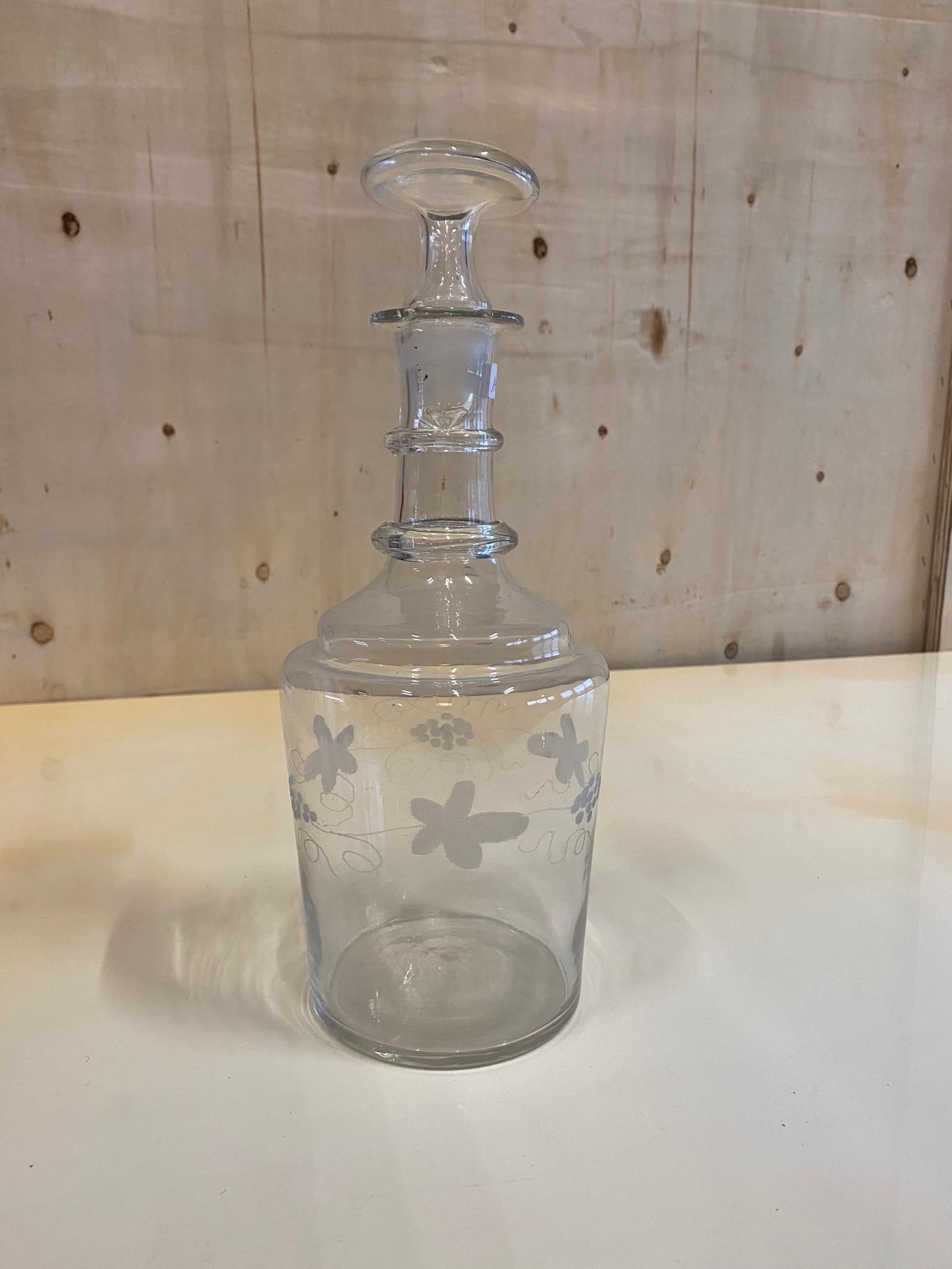 Antique stopper carafe from France from the years around 1900. The carafe has a bulbous body and opens into a narrow neck, which is closed by a stopper. The bulbous part of the carafe is once decorated all around with etched vines and leaves. This