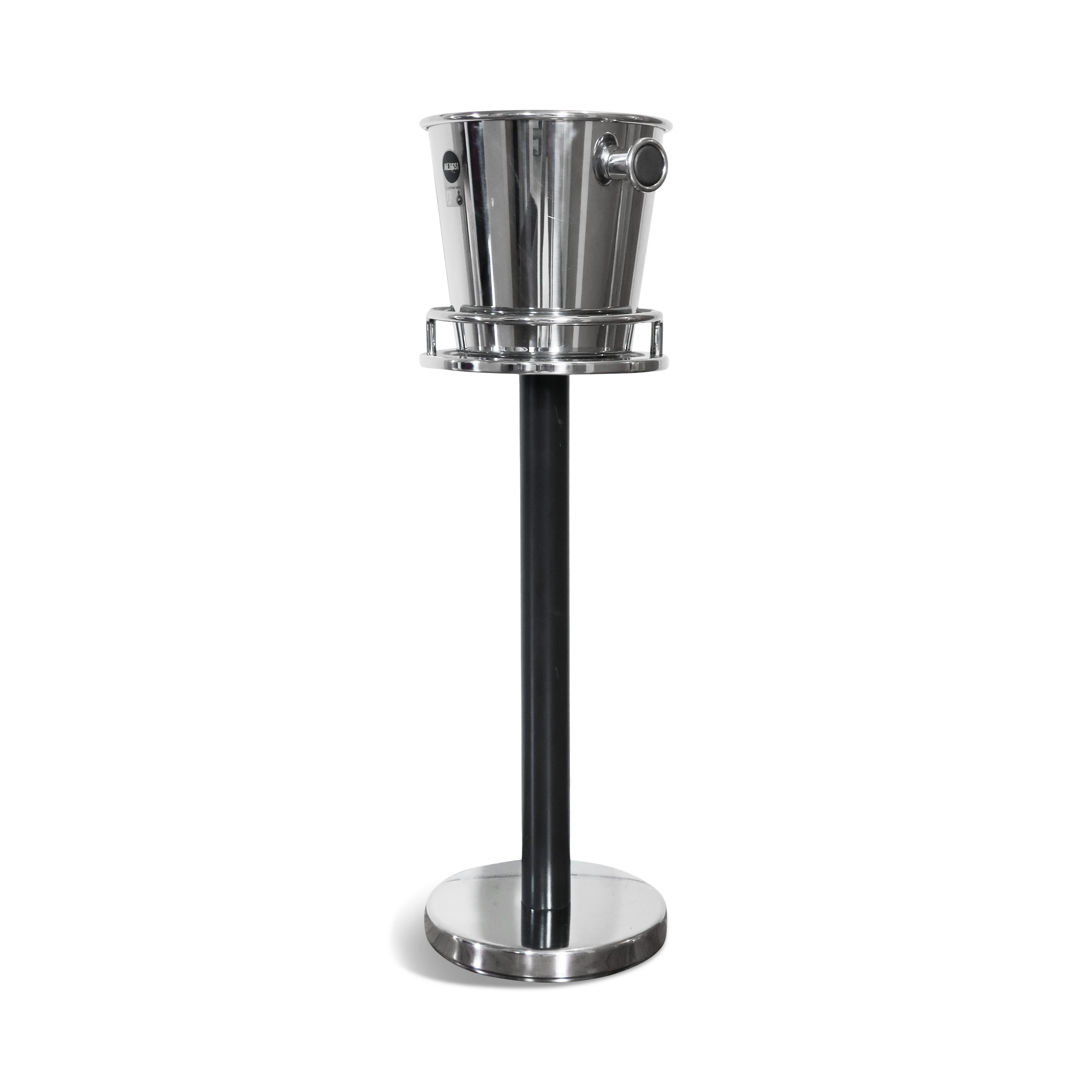 A classic polished 18/10 stainless steel wine cooler and stand designed by Ettore Sottsass for Alessi in 1979. A unique handle design and rolled rim allow getting a perfect grip with just one hand. The stand has a stainless weighted base and top