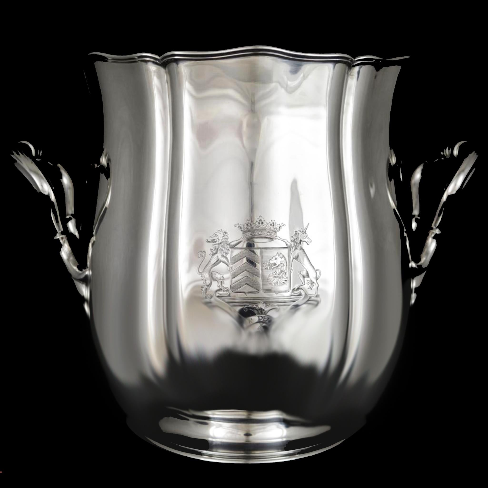 This elegant tulip-shaped champagne bucket a magnum fits, it is resting on a molded bate, edge outlined with bypassed threads. Decor with curved cut sides separated by large grooves, engraved with a coat of arms under a ducal crown.
The side handles