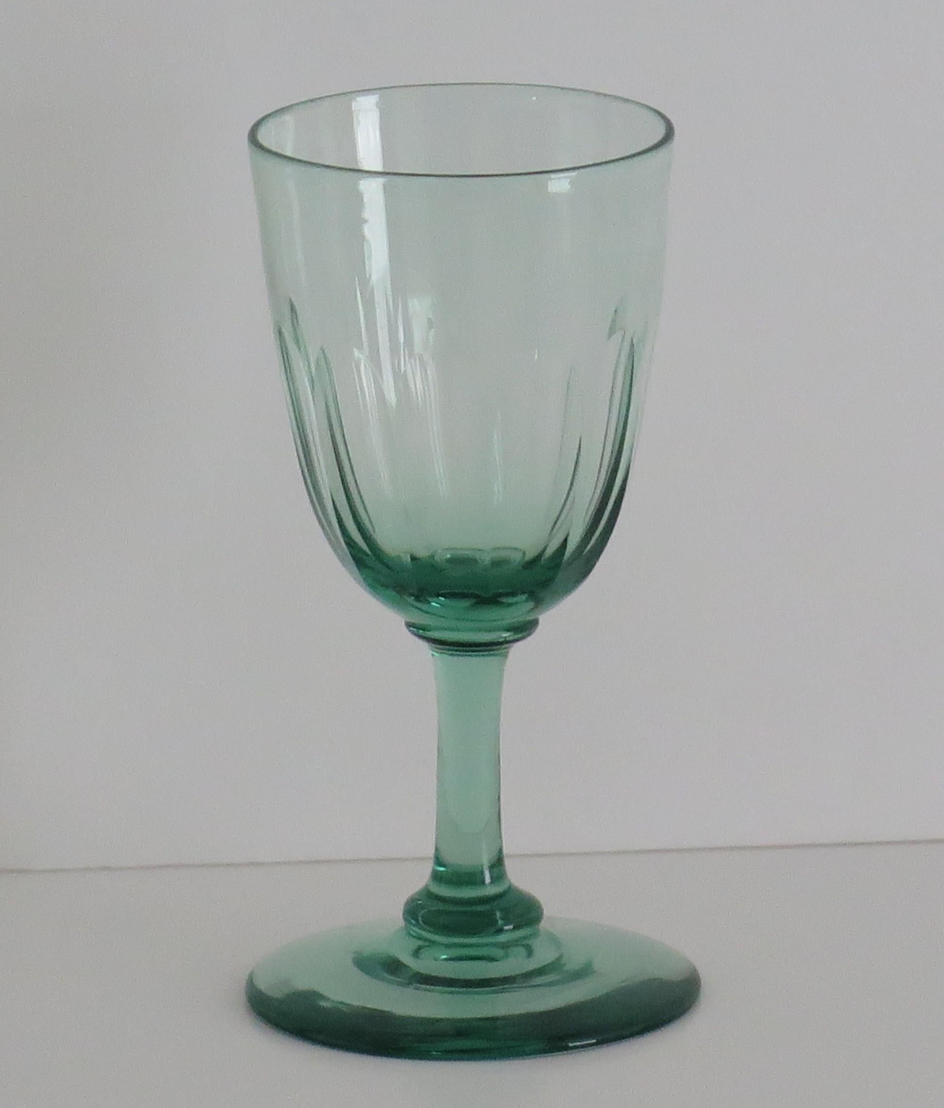 This is a good example of an early Victorian English, hand blown, Light green wine drinking glass, with a panel cut bowl dating to circa 1840.

This glass has a round funnel bowl over a solid stem, which sits on a flattened basal knop on a plain