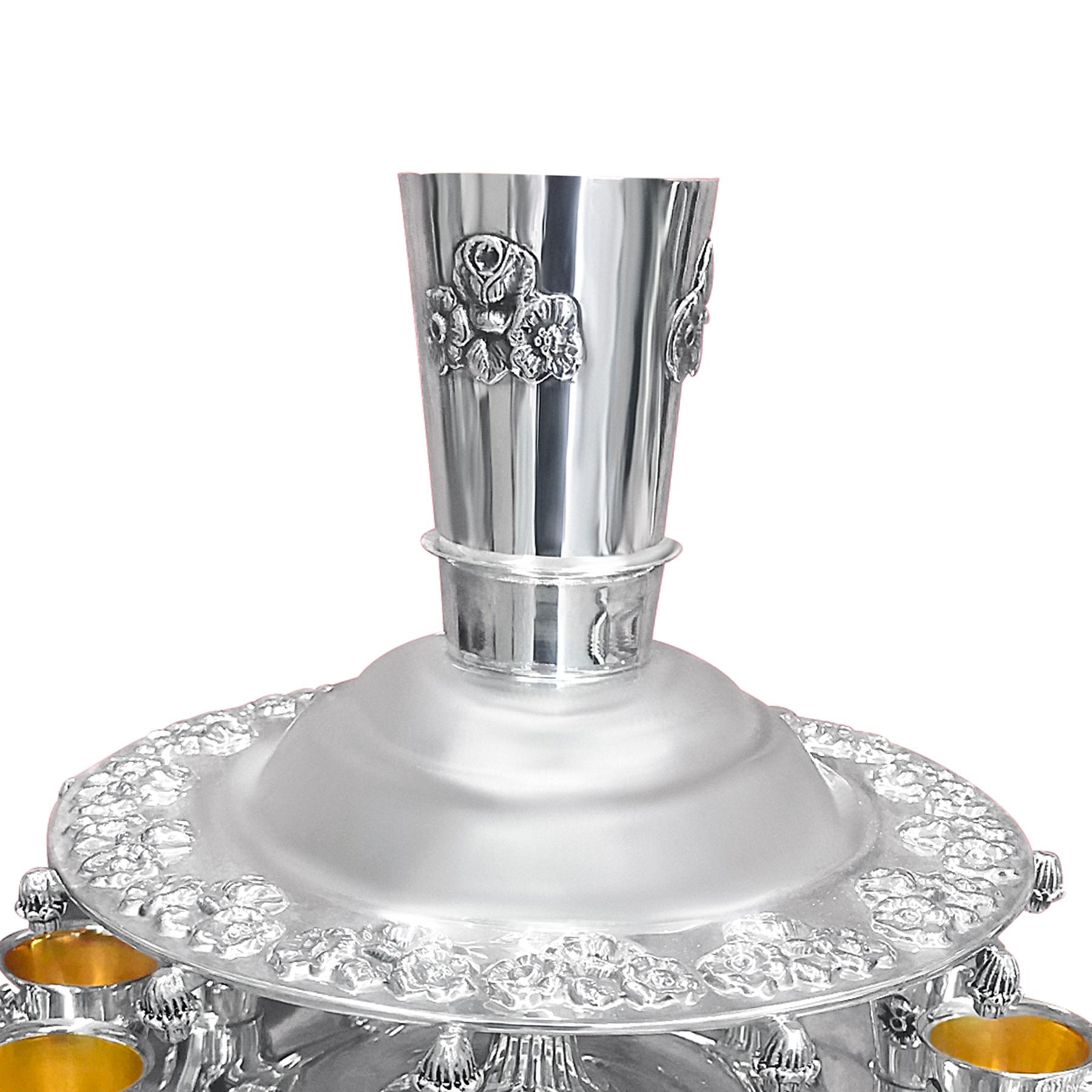 This silver wine fountain is a grace to your table, expressing the greatness that you are. It stands on a plate of floral design that is connected to a flattened silver base from which a big cup rises at the top into which your exotic wine is