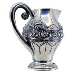 Wine jug in embossed silver with floral motifs and resting on a frilled base