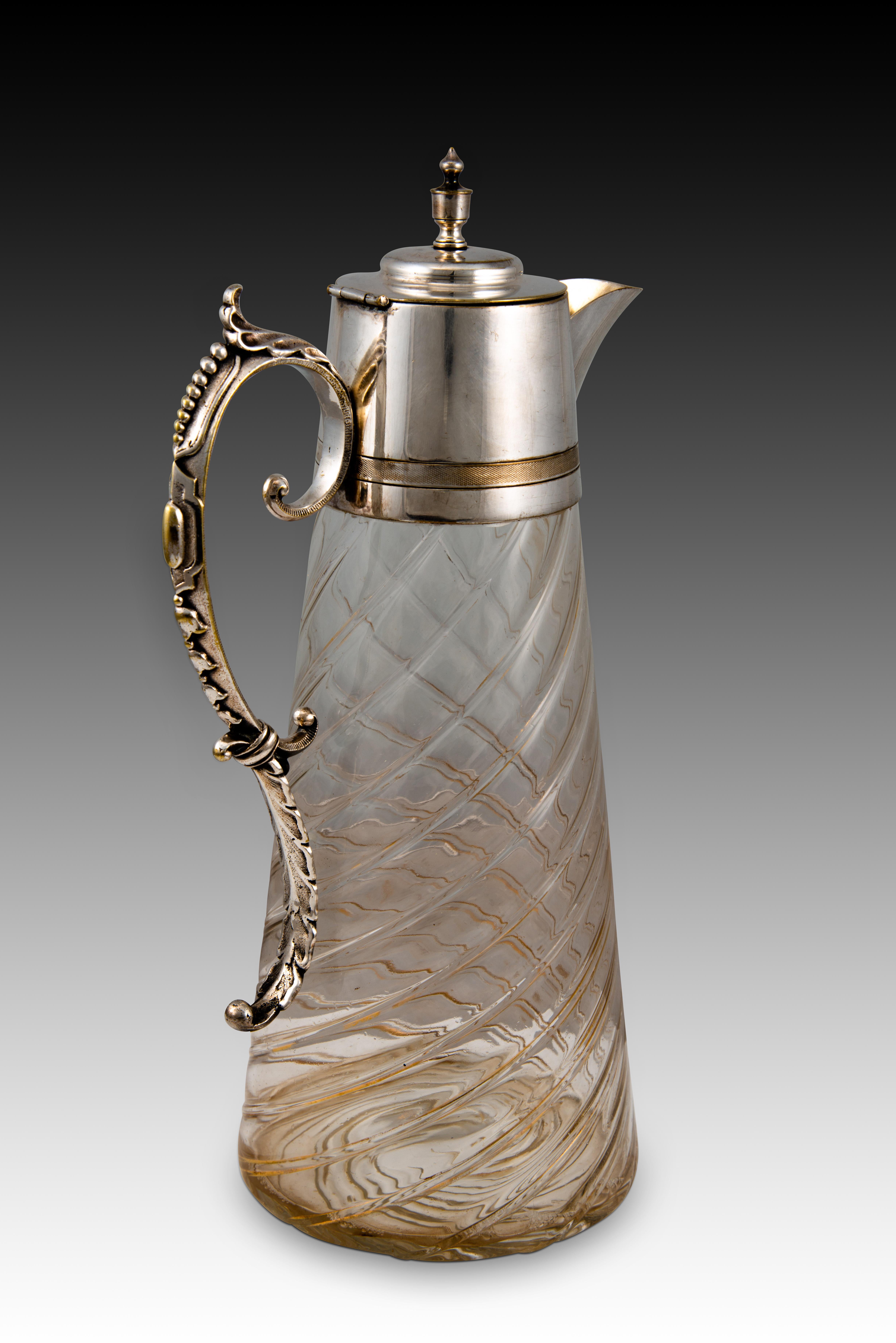 Weinkrug oder Dekanter. Glas, Metall. Zwanzigstes Jahrhundert. 
Krug mit Glaskörper, der mit spiralförmig angeordneten Linien verziert ist. Deckel, Ausguss, Henkel und Deckel aus Silbermetall, verziert mit Elementen, die den Einfluss des