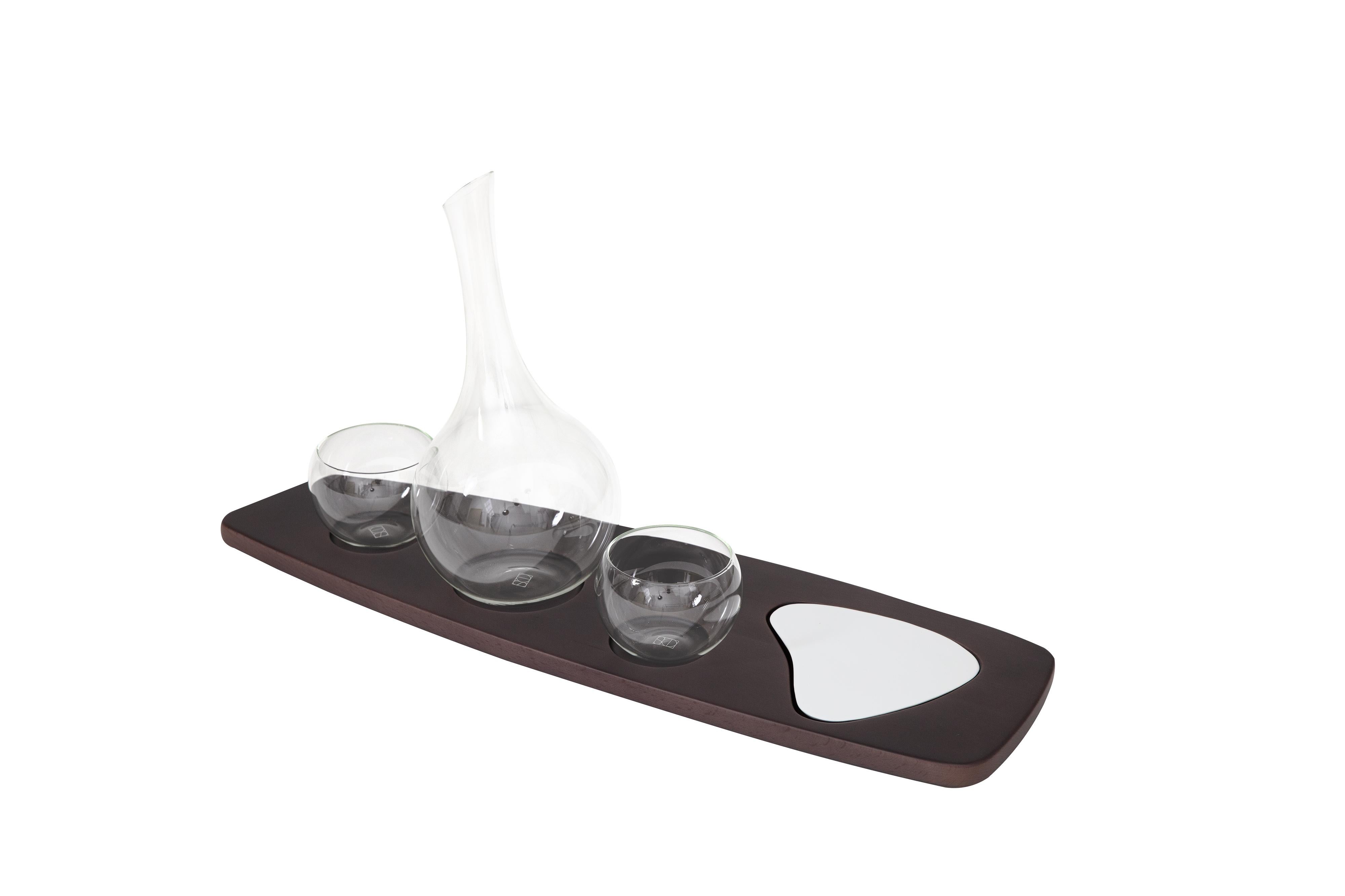 The wine service set is comprised of an organically shaped hand-blown borosilicate glass wine decanter and two glasses that nestle into a slender linear solid beech wood tray complete with a hand-molded white ceramic appetizer plate. 

The Pok