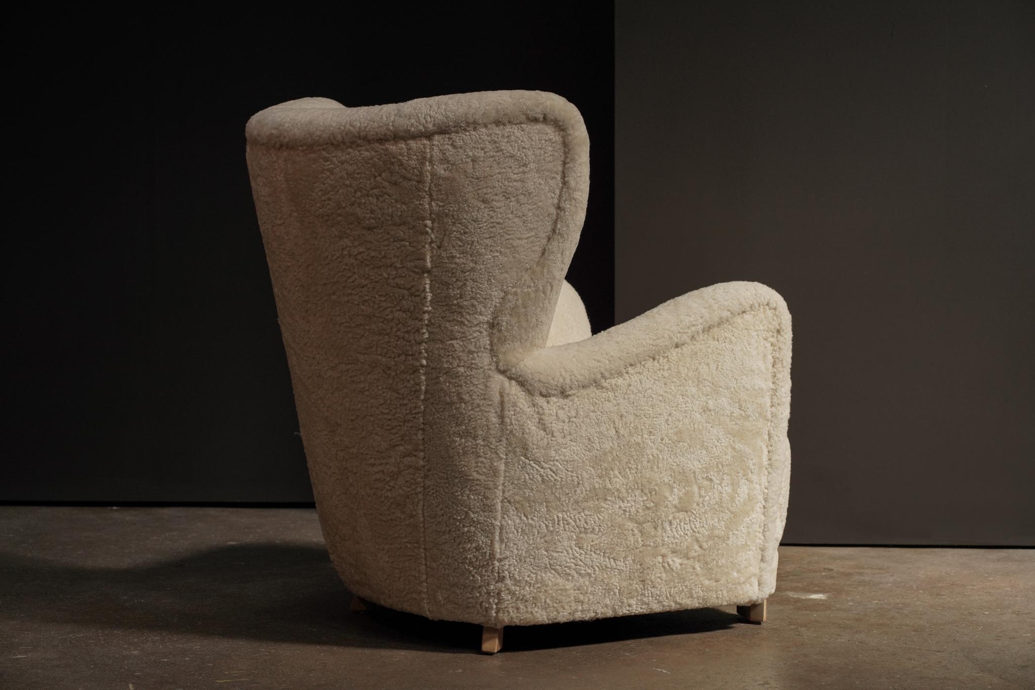 Chaise de salon danoise recouverte de shearling ivoire et reposant sur des pieds en chêne chaud. Sa silhouette douillette et ses matériaux naturels créent une pièce à la fois accueillante et raffinée. Il ferait un excellent fauteuil d'appoint dans