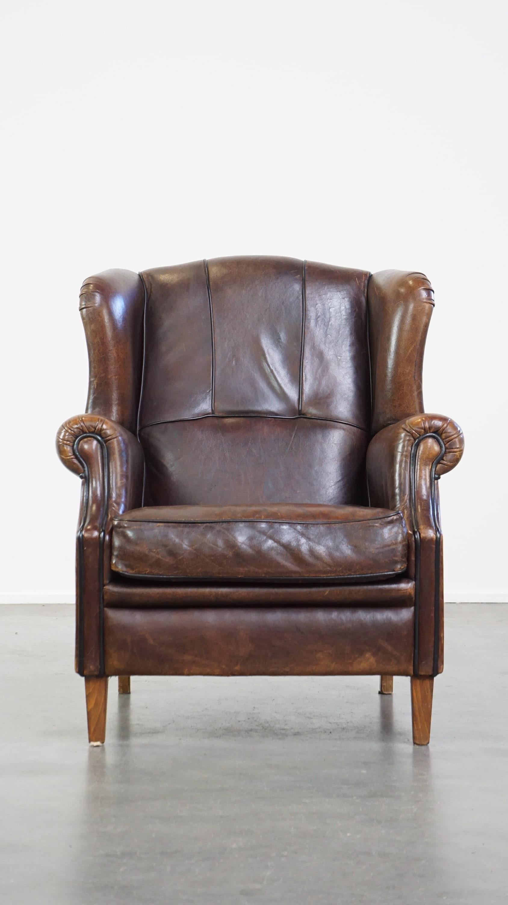 Questa splendida sedia ad ala, realizzata in pelle di pecora, emana tranquillità e calma grazie alla sua finitura elegante con profili neri. A nostro avviso, è un pezzo essenziale per qualsiasi interno. La sedia è dotata di un cuscino di seduta
