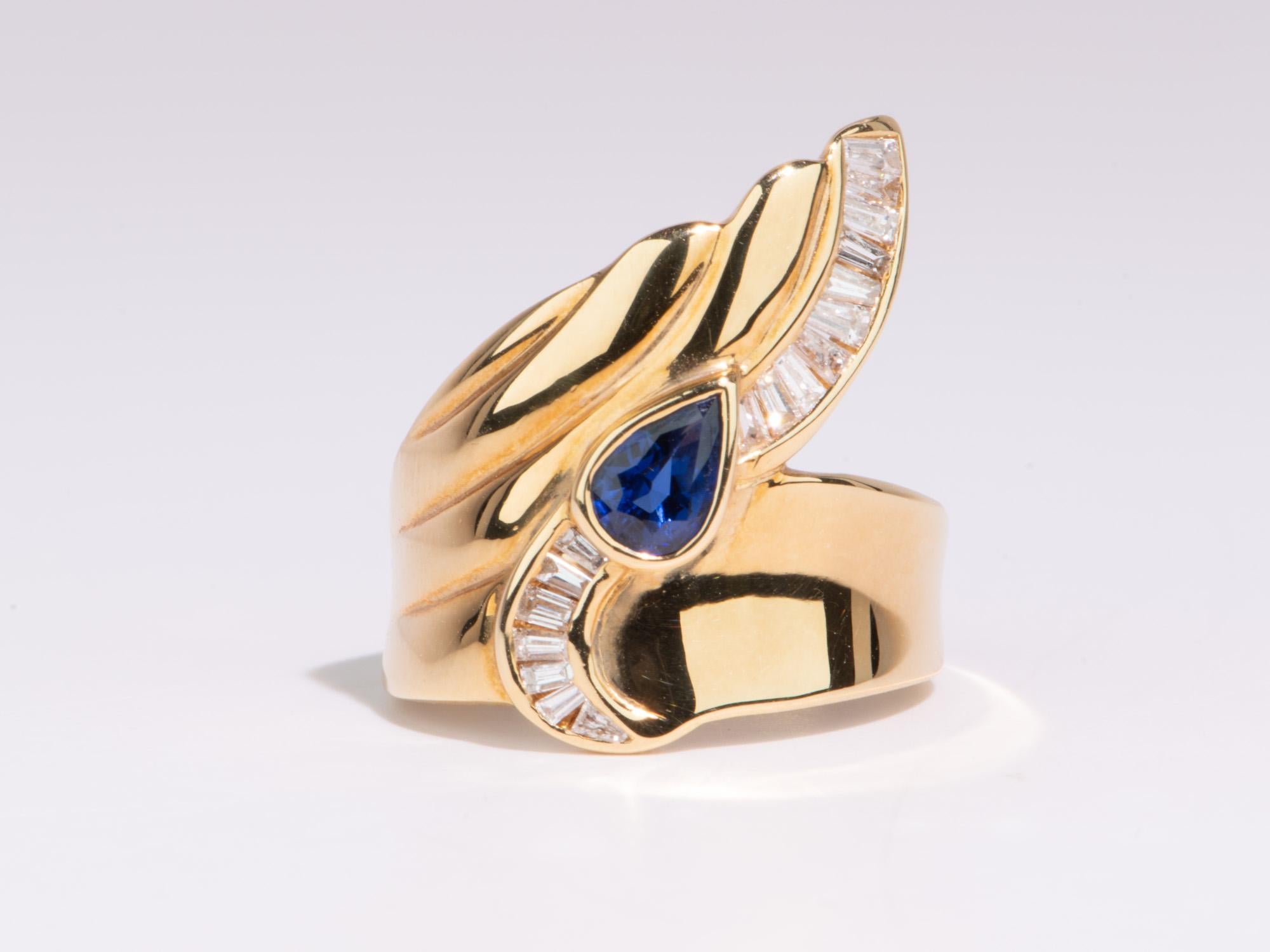 This gorgeous Wing Tip Ring is an exquisite representation of your personal style. The unique flowing design is beautifully complemented by the vivid blue sapphire. Crafted from 18K gold, it weighs 10.7g and is sure to add an elegant touch to any
