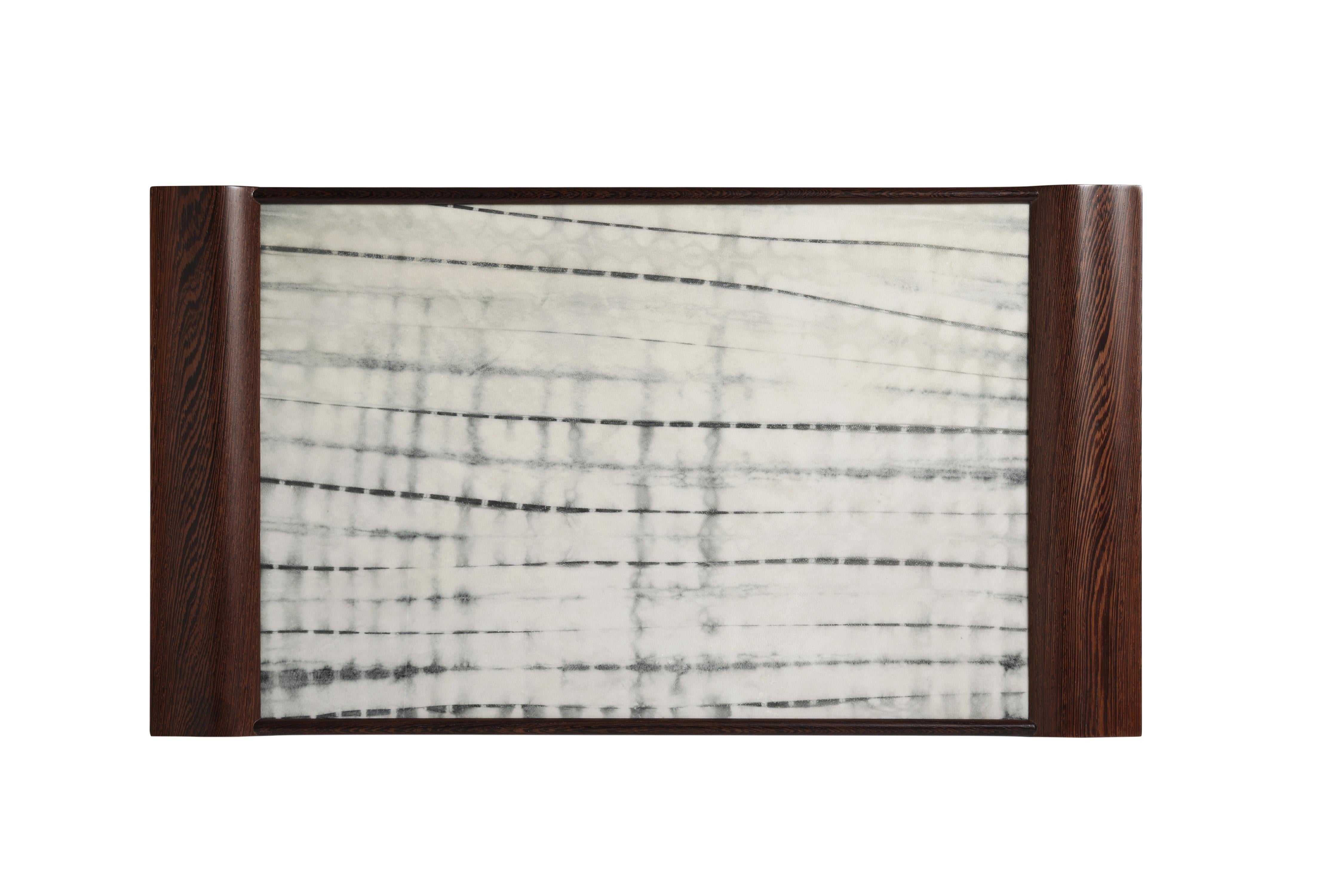 The Wing tray is a marriage of two beautiful natural materials - rawhide and chicken wing wood. The vibrantly-grained Chinese wood has been expertly carved into sweeping wing-like handles. The parchment has been shibori dyed to create soft and