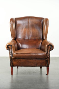 Sillón Wingback de piel de oveja acabado con clavos decorativos