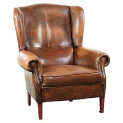 Sillón Wingback de piel de oveja acabado con clavos decorativos