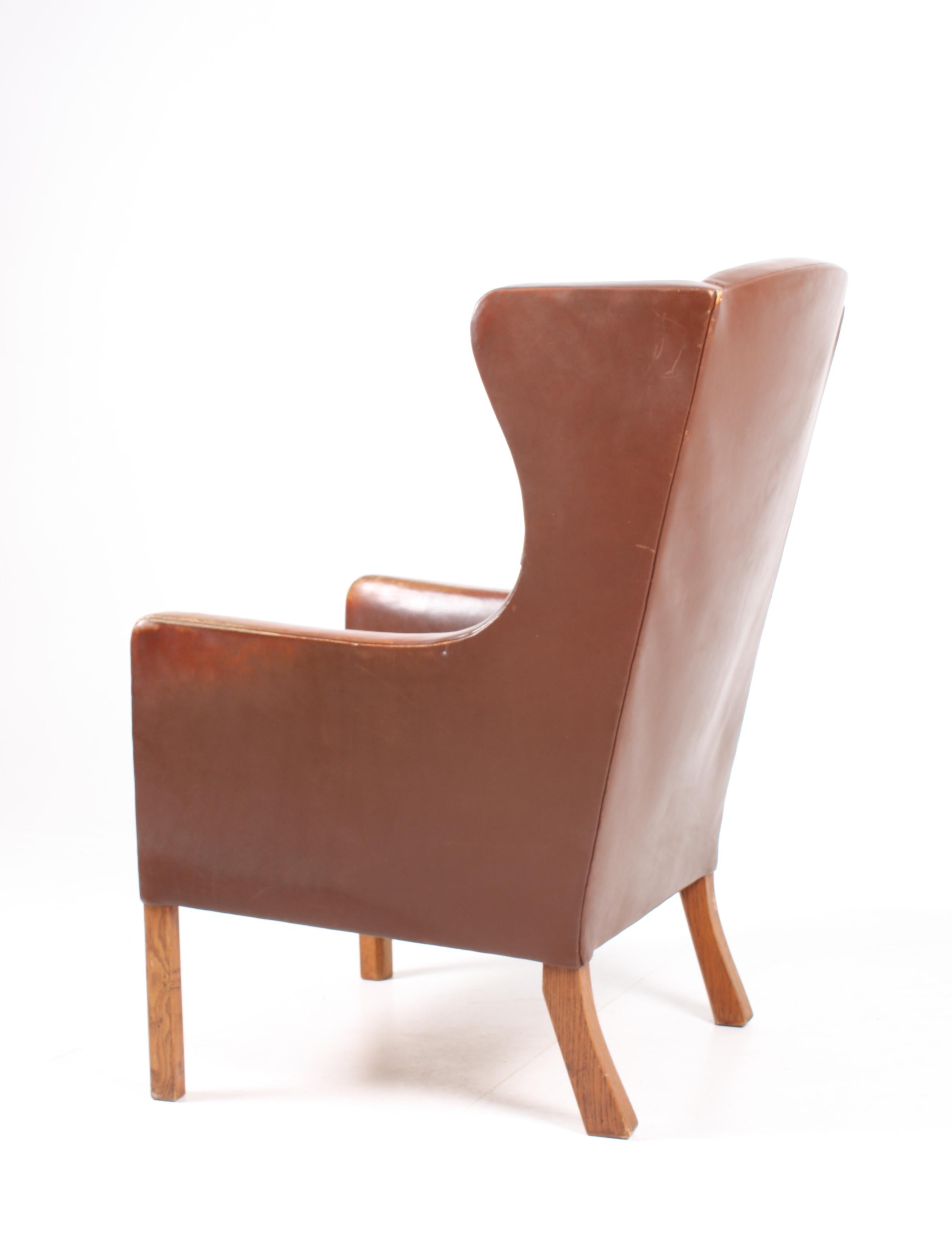 Comfortable wingback chair in well patinated leather on a solid oak frame. Designed by MAA. Børge Mogensen for FDB in 1950. Great original condition. Made in Denmark.