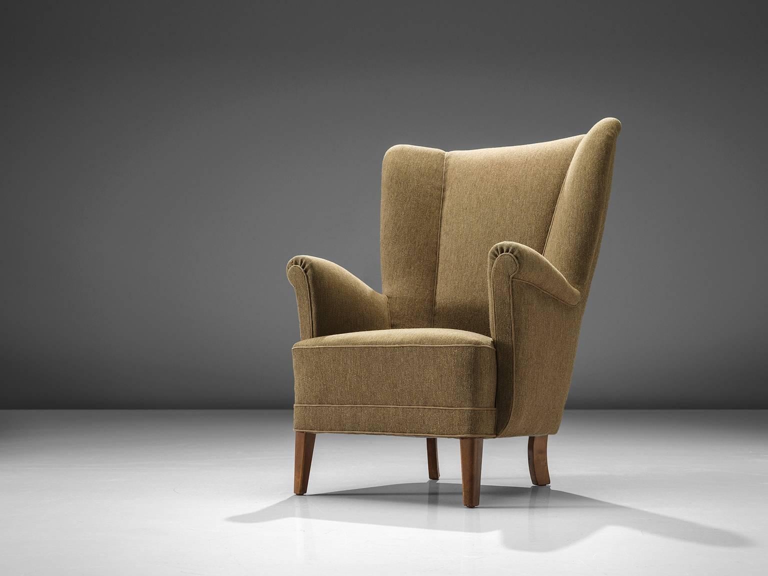 Wingback chair in a classical camel color wool

This easy chair has an aesthetic and ergonomic shape and a classical wing back. 

The seating itself is thick and the armrests rise gracefully upwards. The feet on the front are tapered and the back