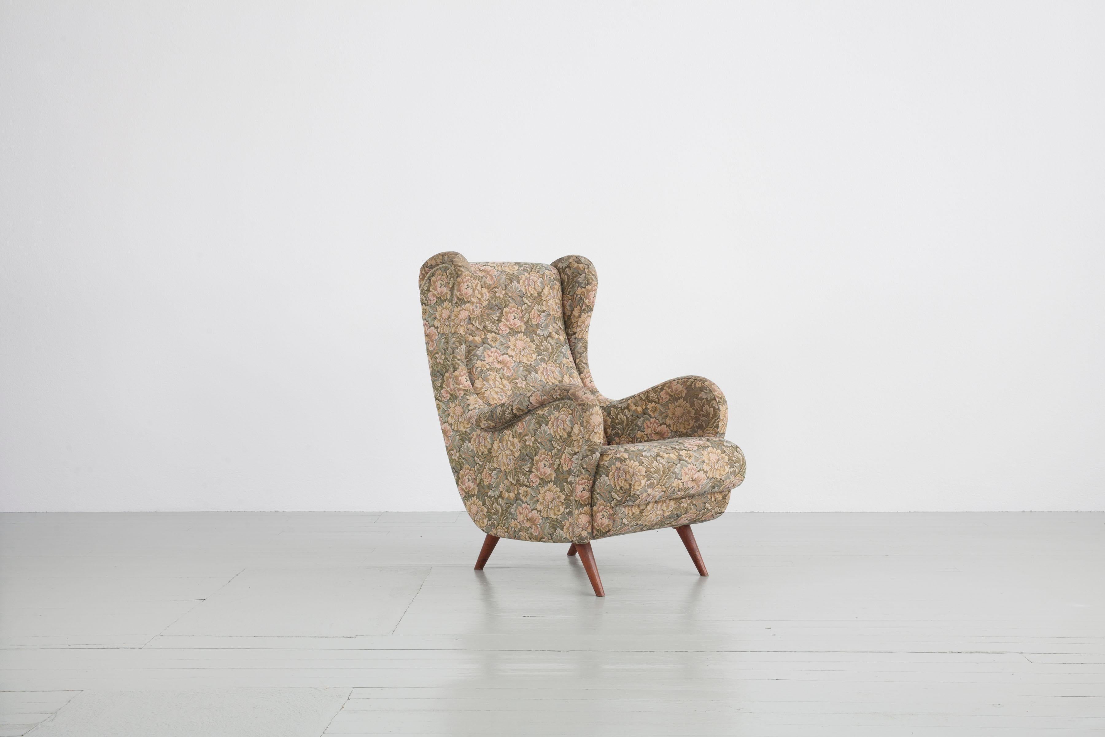 Wingback chair from Italy, 1950s. The chair features an exceptional curved armrest and is upholstered with floral patterned fabric which can be re-upholstered. 

Feel free to contact us for more detailed pictures.
