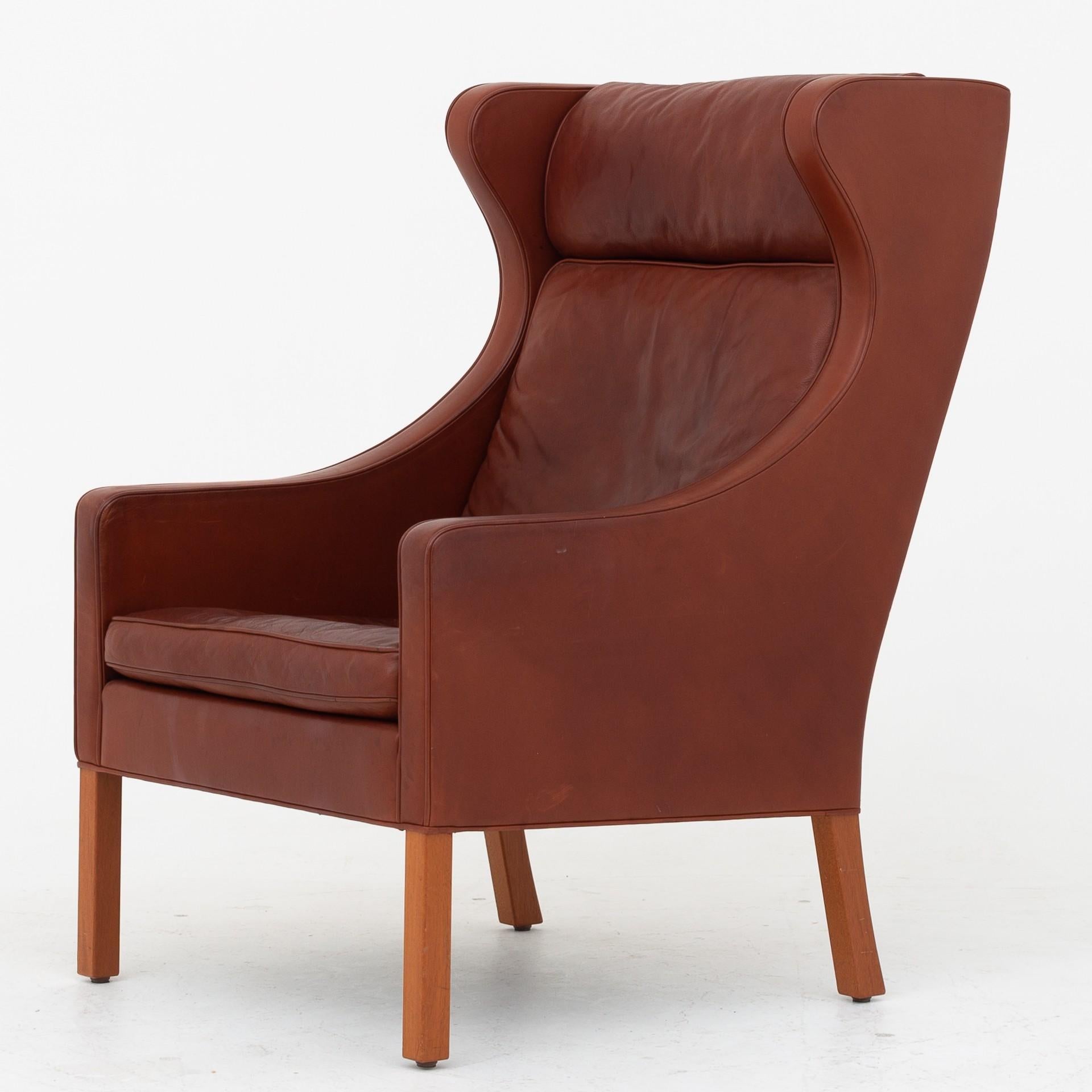 Wingback chair (BM 2204) with stool (BM 2202) in original reddish/brown leather and legs of mahogany. Maker Fredericia Furniture.