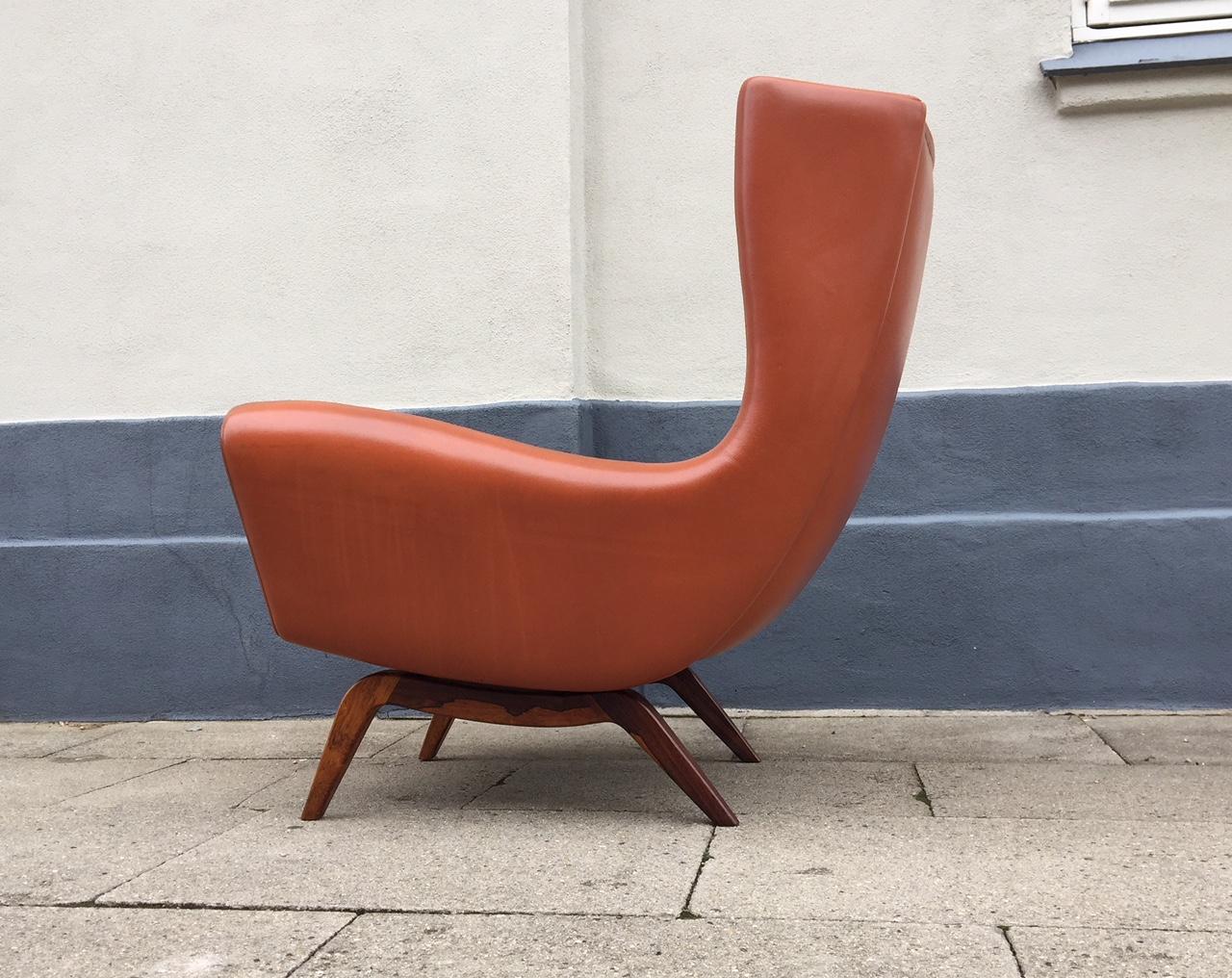 This highback easy chair in cognac-colored leather was designed by Illum Wikkelsø in 1959 and manufactured by Søren Wiladsen in Denmark. This chair is commonly referred to as model SW 110 and also features solid Brazilian rosewood legs that have