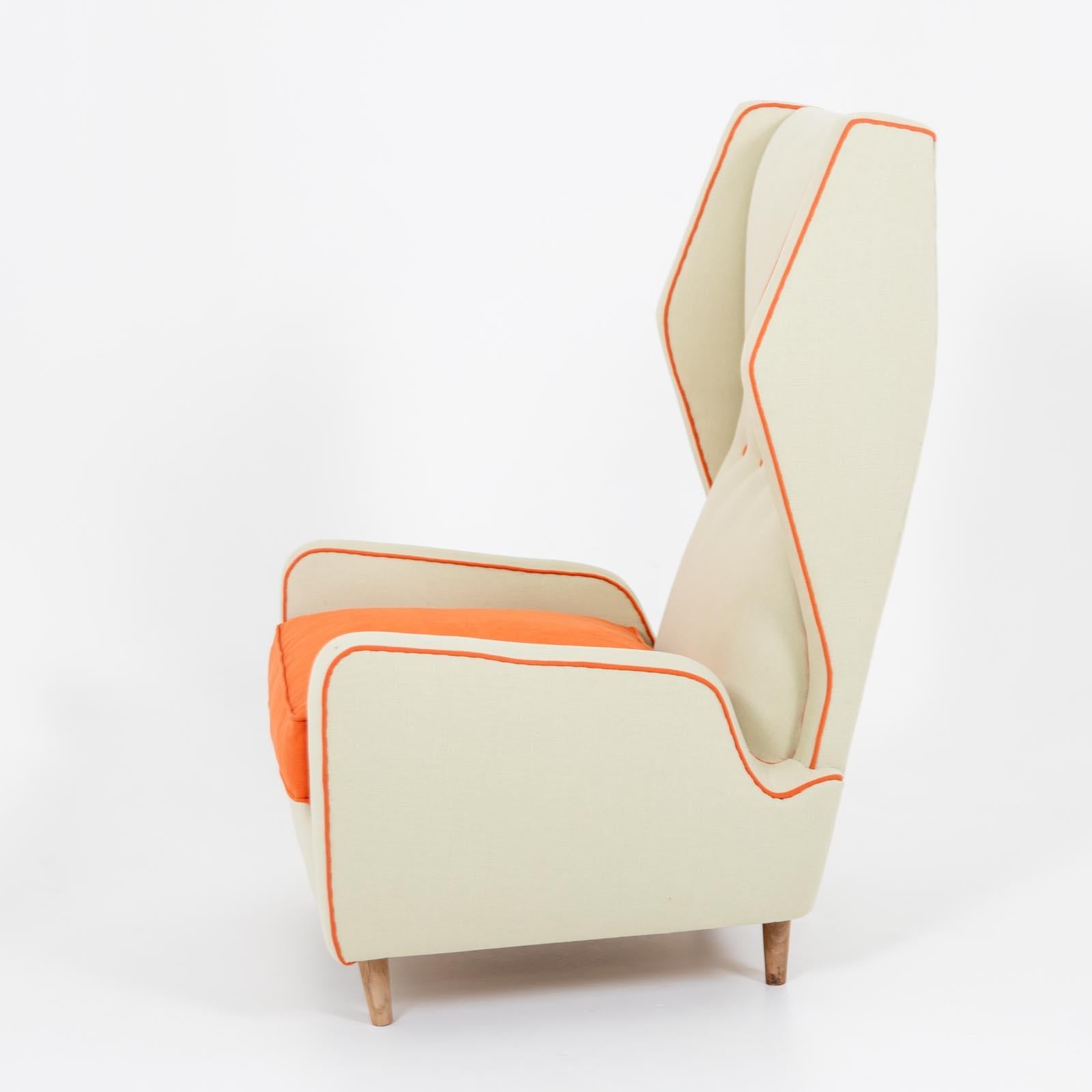 Italian mid-century lounge chair with high backrest and armrests. The armchair has light-colored upholstery and is accentuated by orange piping with cushions and buttons.