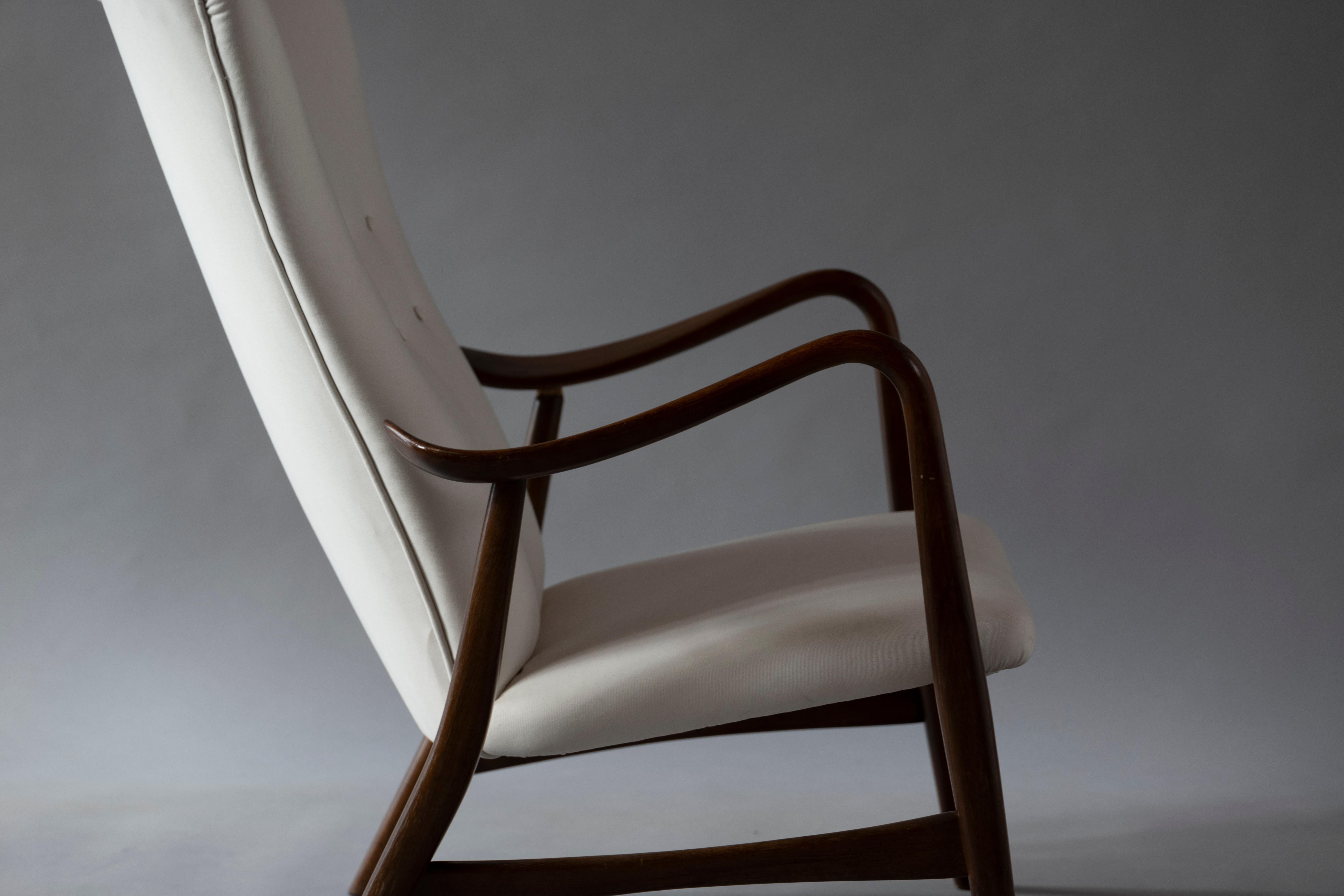 Sculpural wingback lounge chair designed by Schubell & Madsen, Denmark 1950s, curvilinear walnut-stained beechwood frame and armrest, upholstered in white Kvadrat fabric.