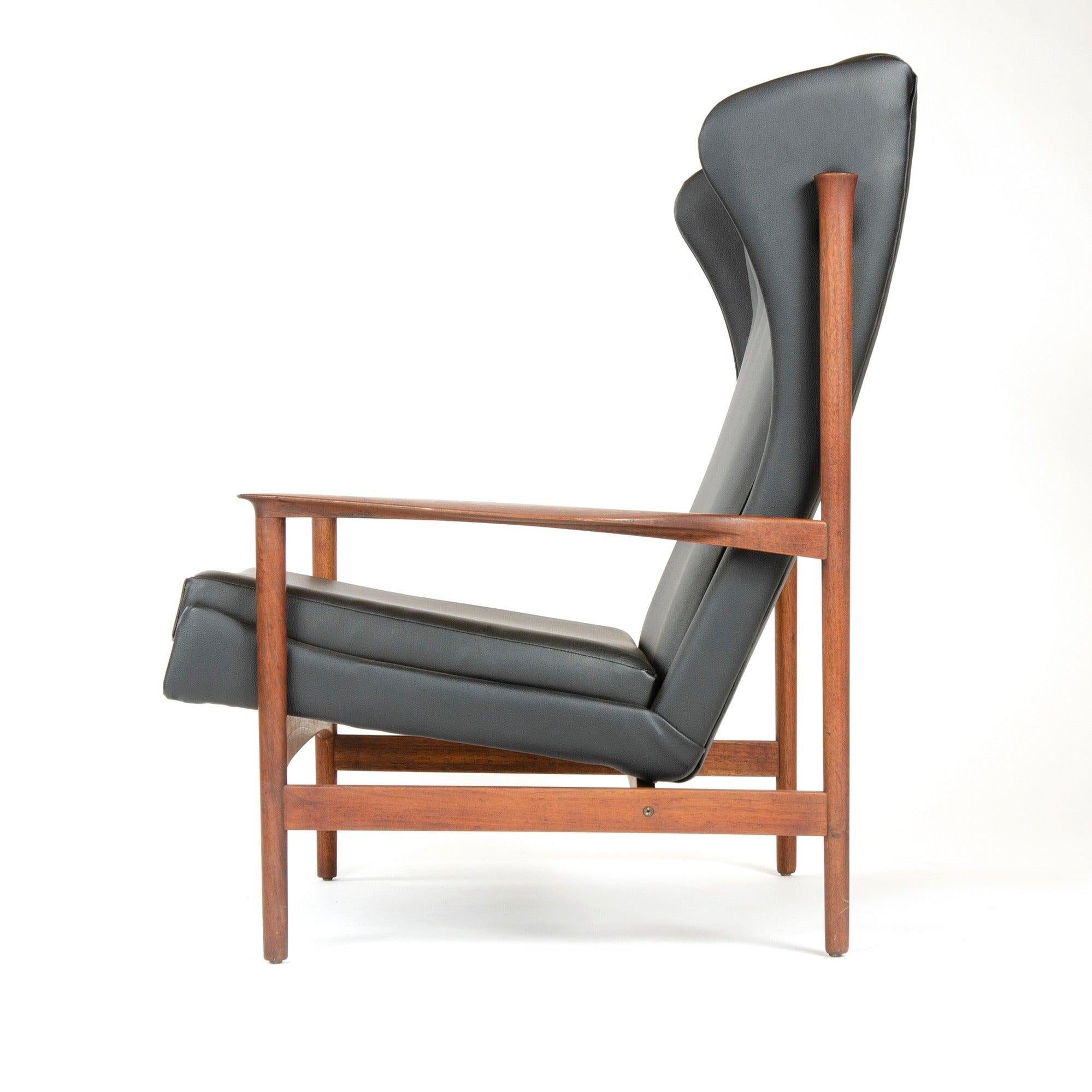 Fauteuil de salon en vinyle noir avec dossier à oreilles touffeté, dont la structure exposée finement jointe supporte un siège sculptural flottant.