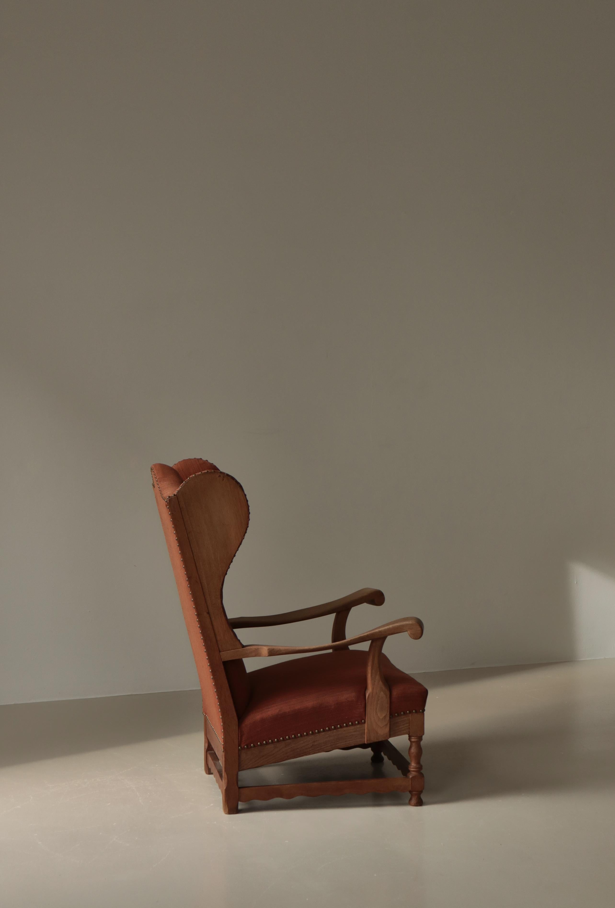 Silla grande con respaldo alado fabricada por un ebanista danés en la década de 1940. Roble macizo con una veta y una pátina maravillosas. Tapicería original de lana naranja quemada y clavos de latón.