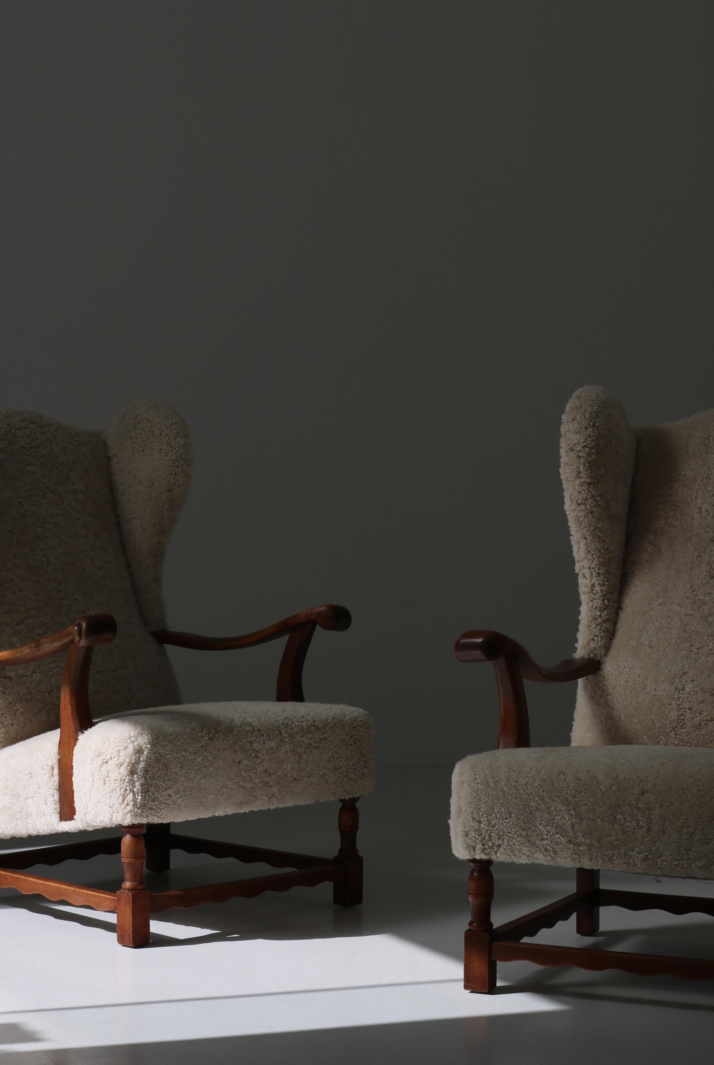 Stunning pair of large expressive wingback chairs made by a Danish Cabinetmaker in the 1940s. The chairs are made from solid Scandinavian oak and has been reupholstered in light organic sheepskin.
 In the style of Fritz Hansen, Henning Kjærnulf and