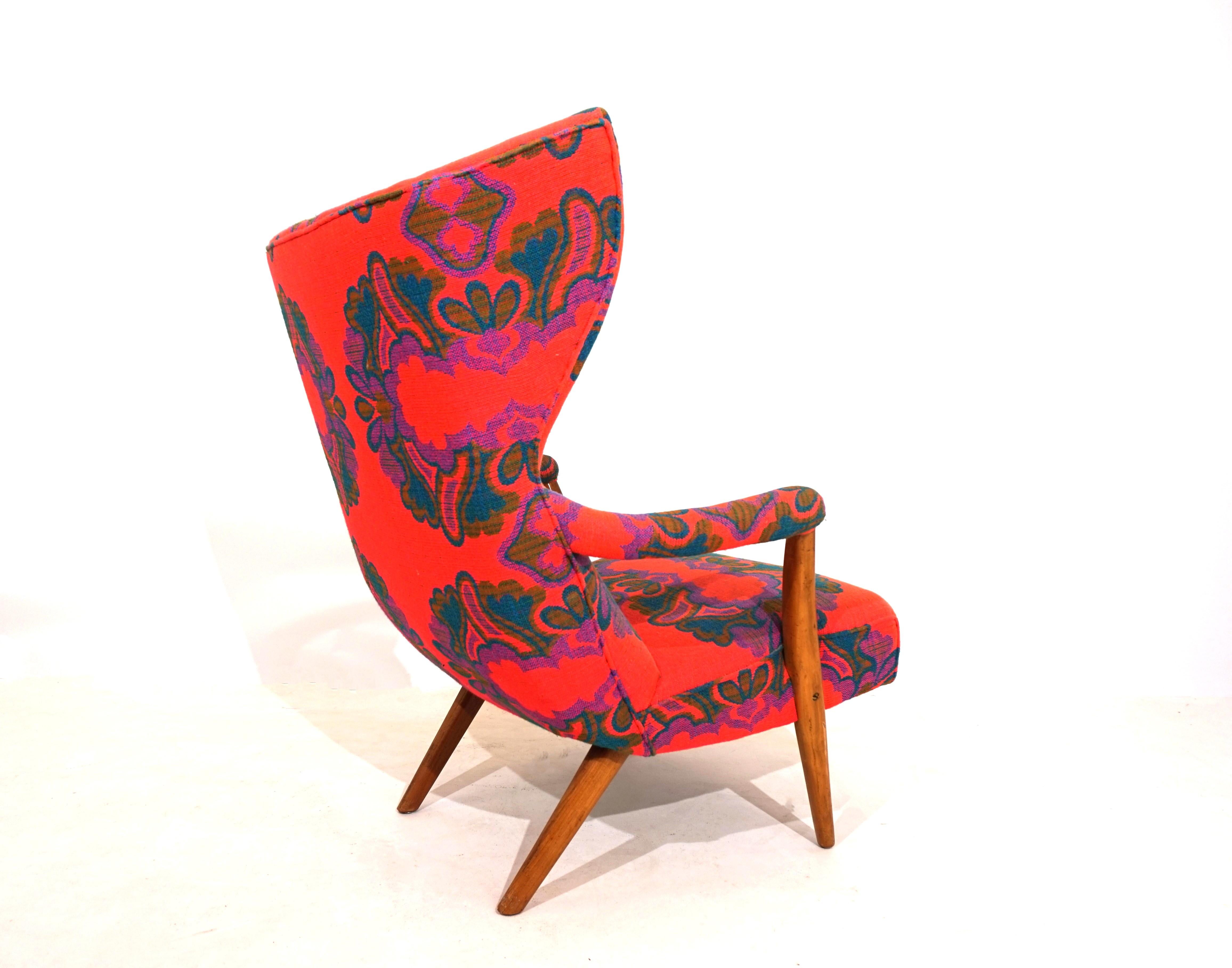 This extraordinary armchair comes in a colorful dress and in very good condition. The dramatic lines of the armchair and the fantastic, coarse fabric designed in great colors and patterns make this armchair the highlight of any room. The armrests