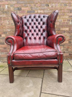 Winged armchair upholstered in deep buttoned red leather, English 1930