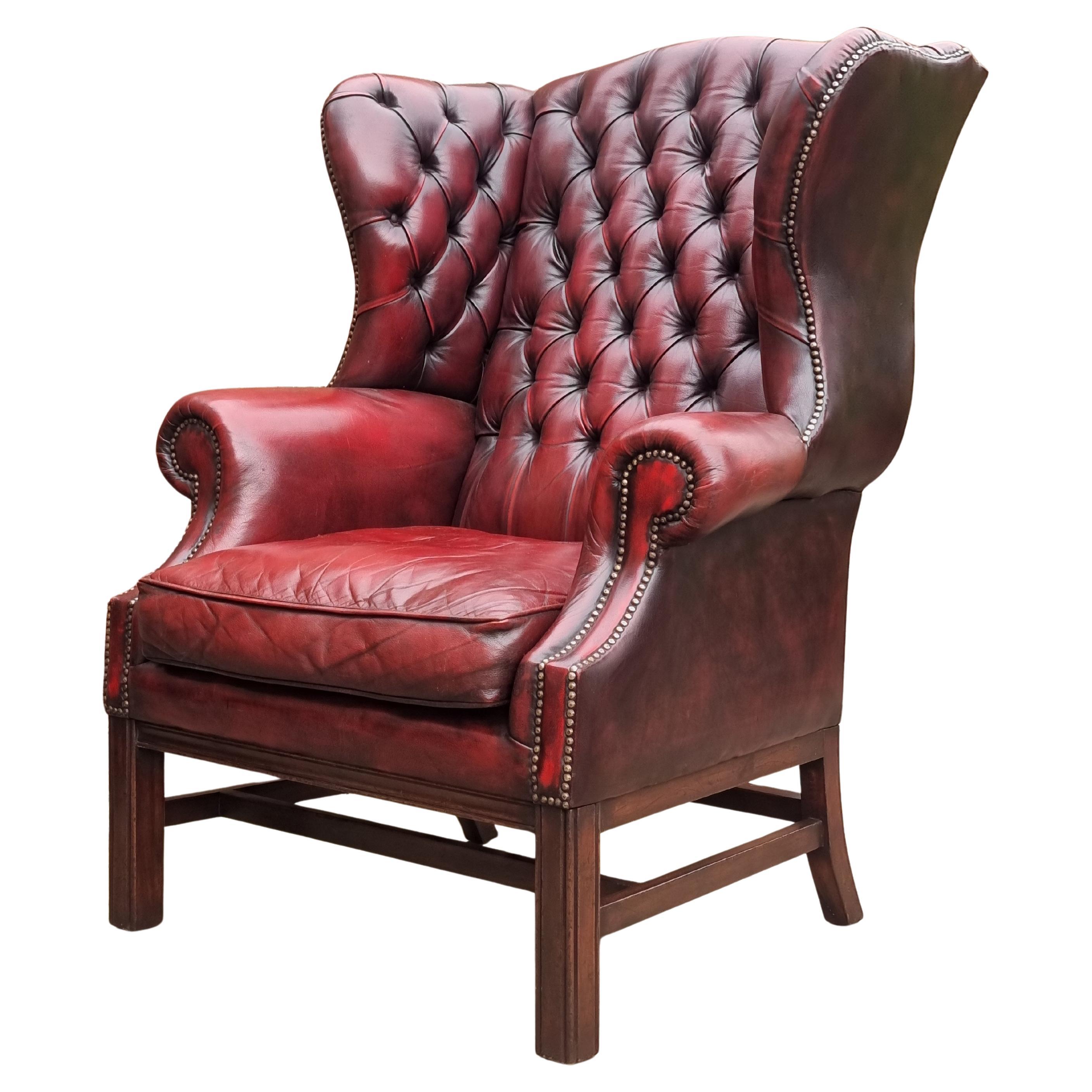 Winged armchair upholstered in deep buttoned red leather, English 1930 For Sale