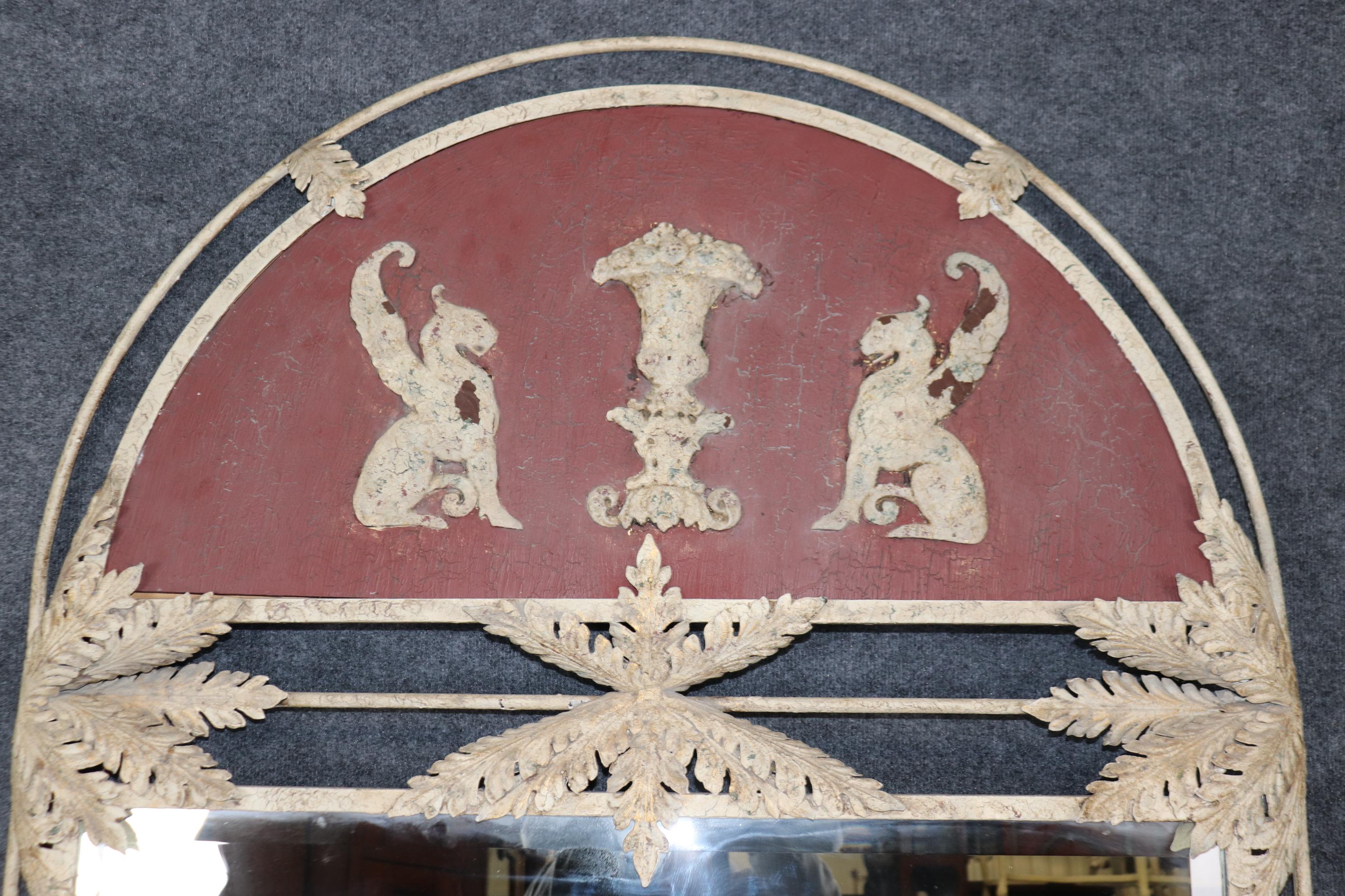 Il s'agit d'un énorme et impressionnant miroir en fer forgé et gesso de style néoclassique avec des griffons ailés en gesso et un magnifique cadre polychrome. L'usure et l'âge sont volontairement atténués. Mesure 84 de haut x 44.75 de large x 3.5