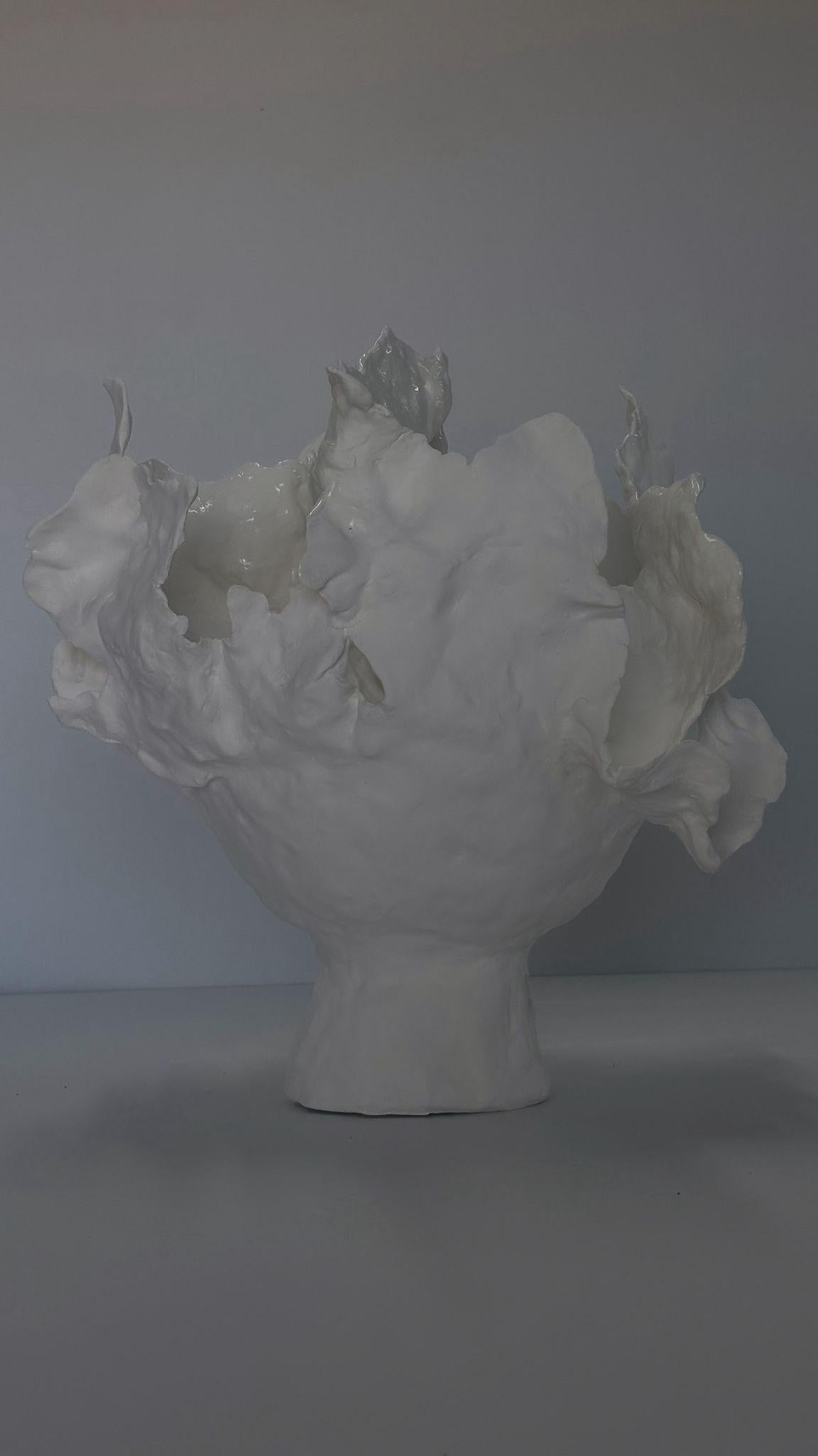 Questo vaso è realizzato interamente in porcellana bianca, un materiale puro e luminoso che sembra portare con sé una luce interiore. Il suo bianco è più di un semplice colore: è una presenza, una sorta di vuoto invitante, come una pagina bianca che