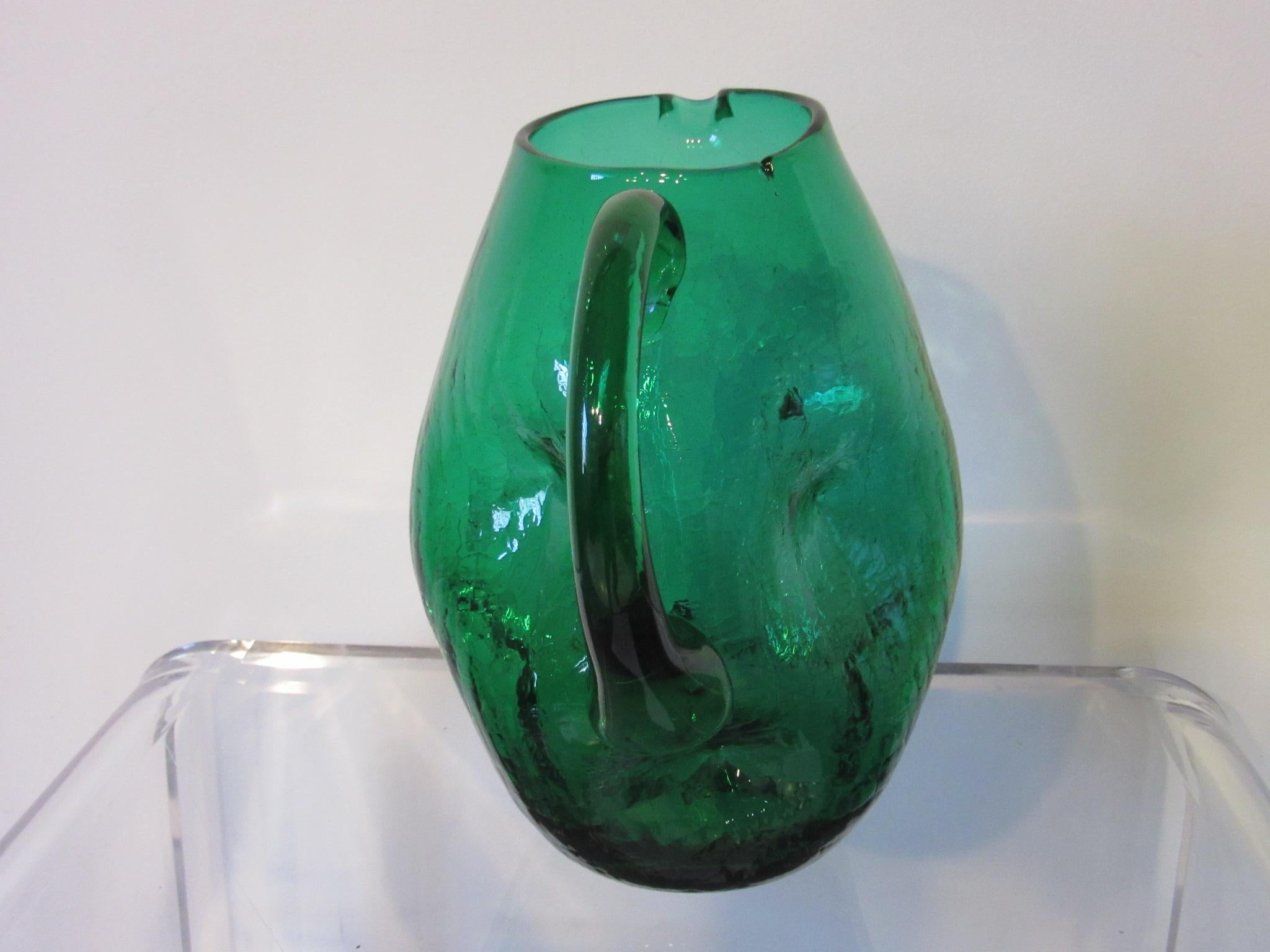 A sculptural crackle pitcher vase with dented design handcrafted by Winslow Anderson for the Blenko Glass Company .