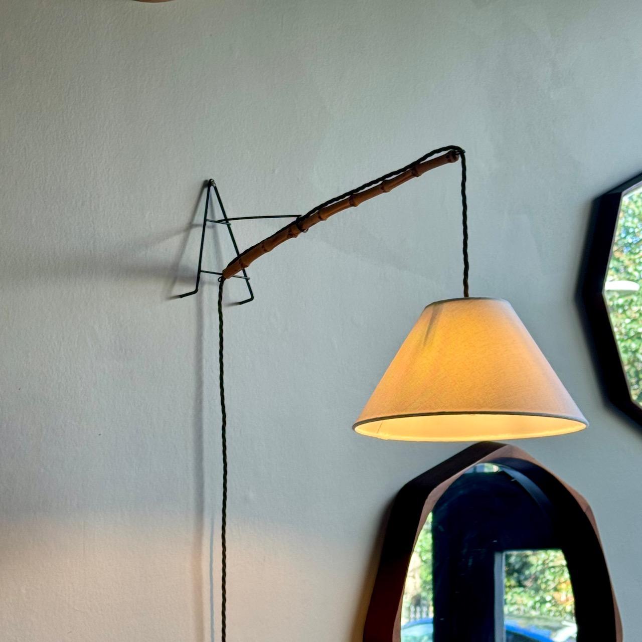 A slim, mid-century wall light with bamboo armature. 

This wall light dates to the 1950s, and would have been perfectly placed in a scheme of complementary rattan furniture, a popular material for domestic furniture which found renewed popularity