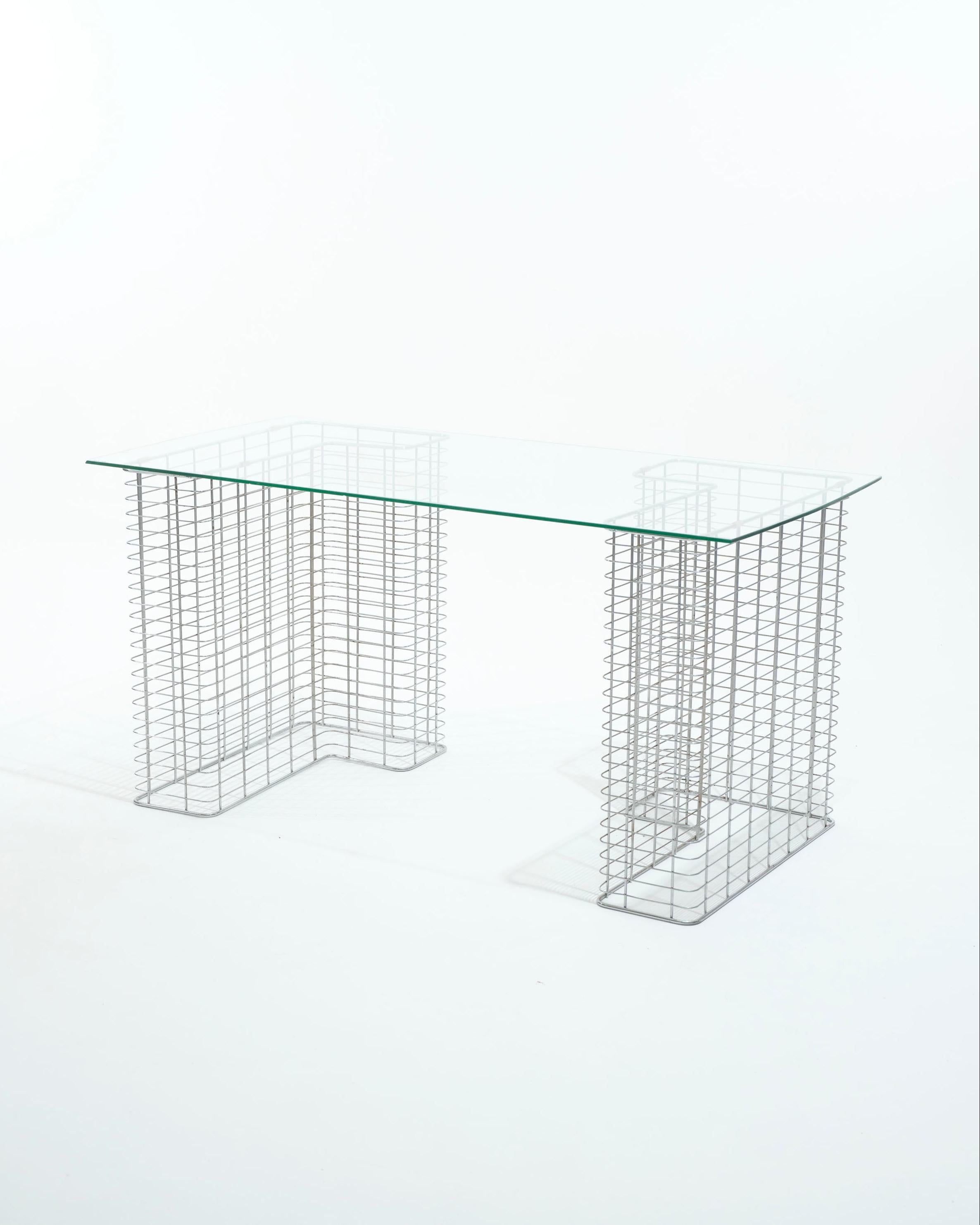 Escritorio grande diseñado por Terence Conran para Habitat en la década de 1980.
Tiene dos patas de metal cromado en forma de L y una amplia tapa de cristal transparente.

La estructura es modular: las patas pueden colocarse verticalmente para