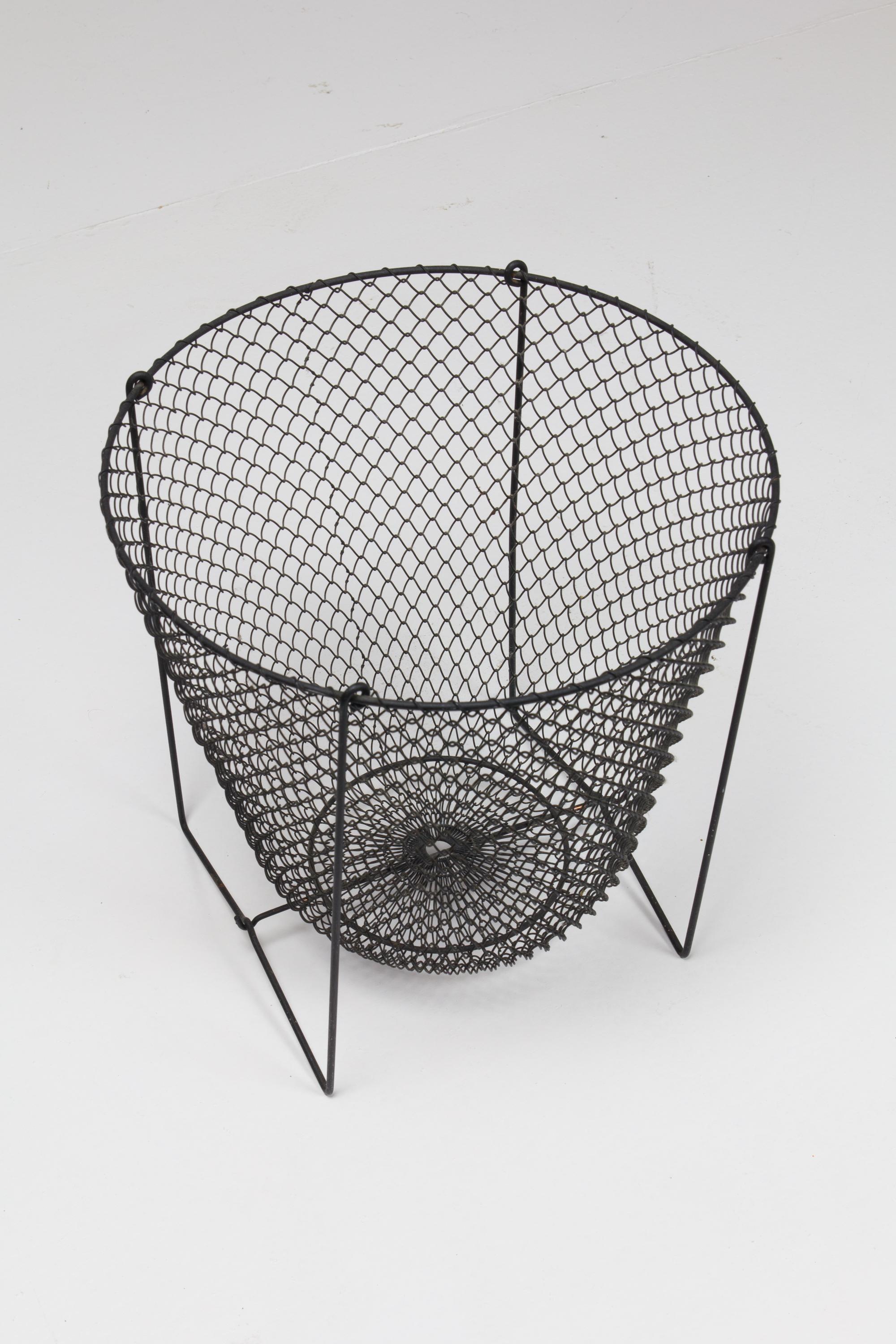 Unusual wastepaper bin comprised of thin wire and wire basket mesh suspended on frame.
