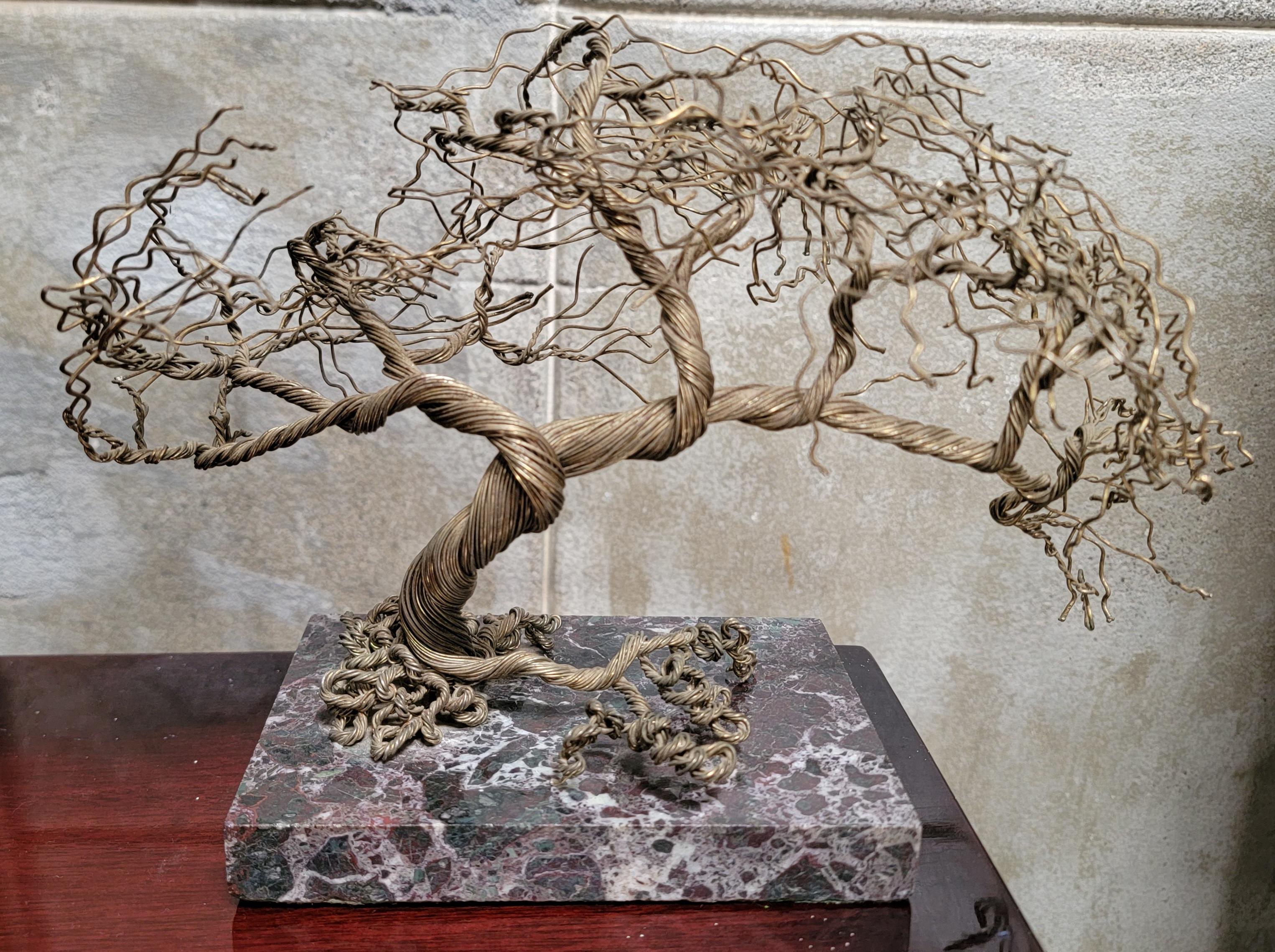 A table top twisted brass wire sculpture of a tree. Mounted to a marble base with an undecipherable signature inscribed in marble.

11 inches wide.
8 inches high.
6.5 inches deep.

Marble base:
6 inches wide.
4 inches deep.