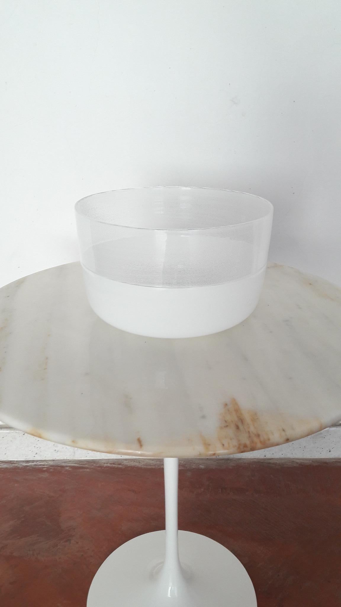 An elegant art-glass bowl designed by Tapio Wirkkala in 1970s and manufactured in Italy by Venini in 1980.
White-milk centerpiece with the upper part made in ‘Filigree’ and the lower part in ‘Opaline’ hand- blown glass with ’Incalmo’