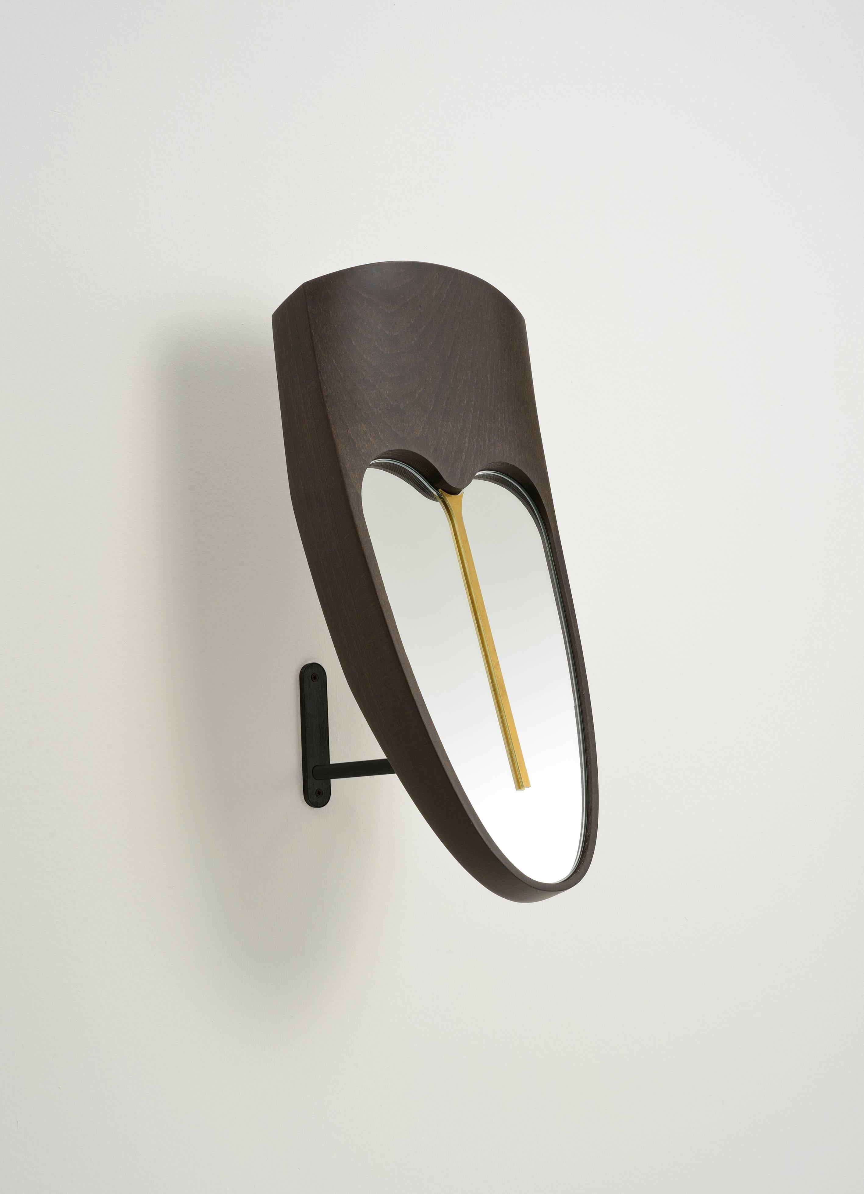 A functional mirror for a dressing room, or wooden masks and sculpture for your living or your entrance. The forehead mask Eze, is made of solid beech wood Wengè finishing, with a brass element on the mirror. The base is an iron stand black
